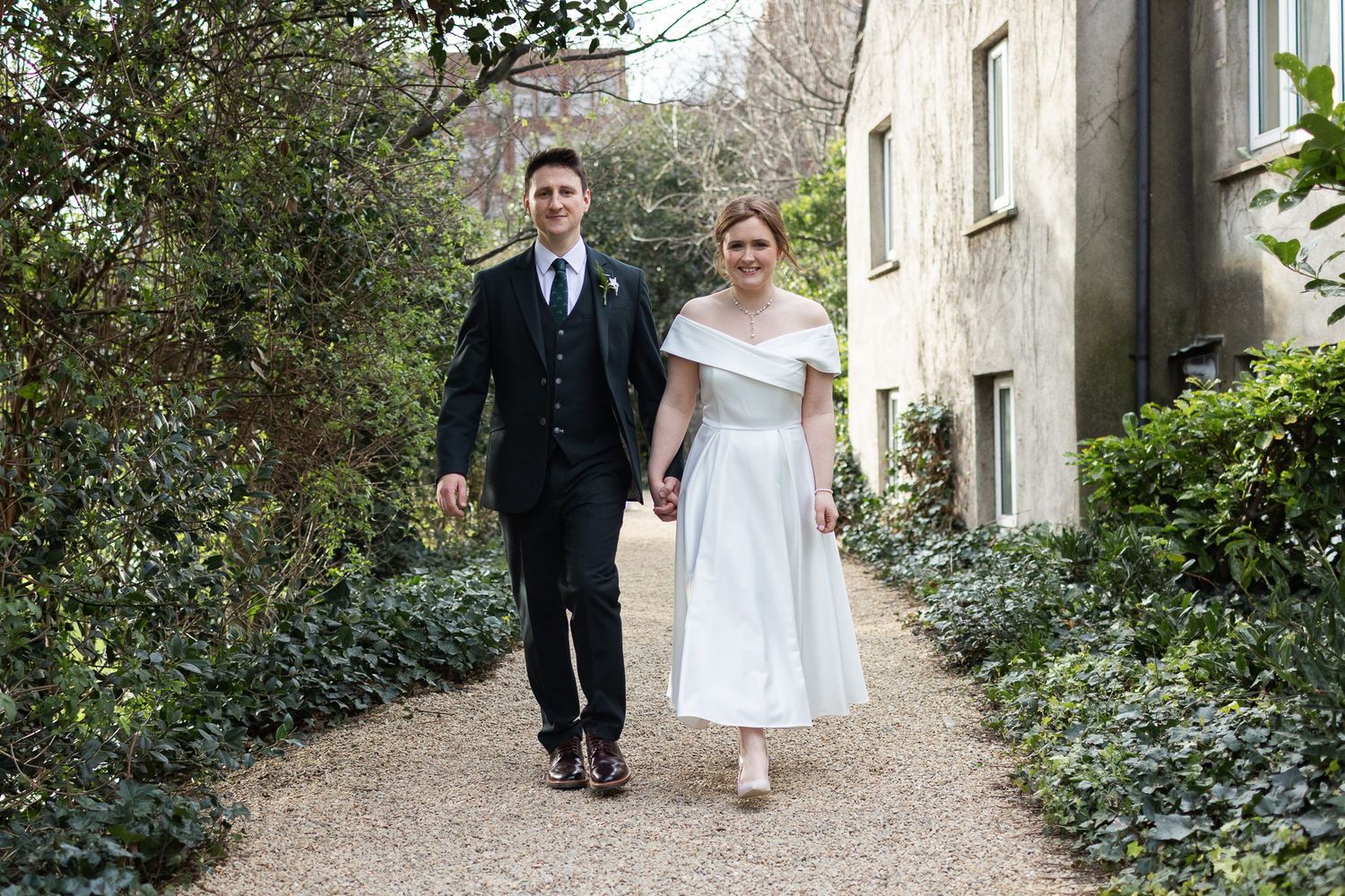Candid Dublin wedding photos of a couple walking and embracing in a Dublin garden setting.