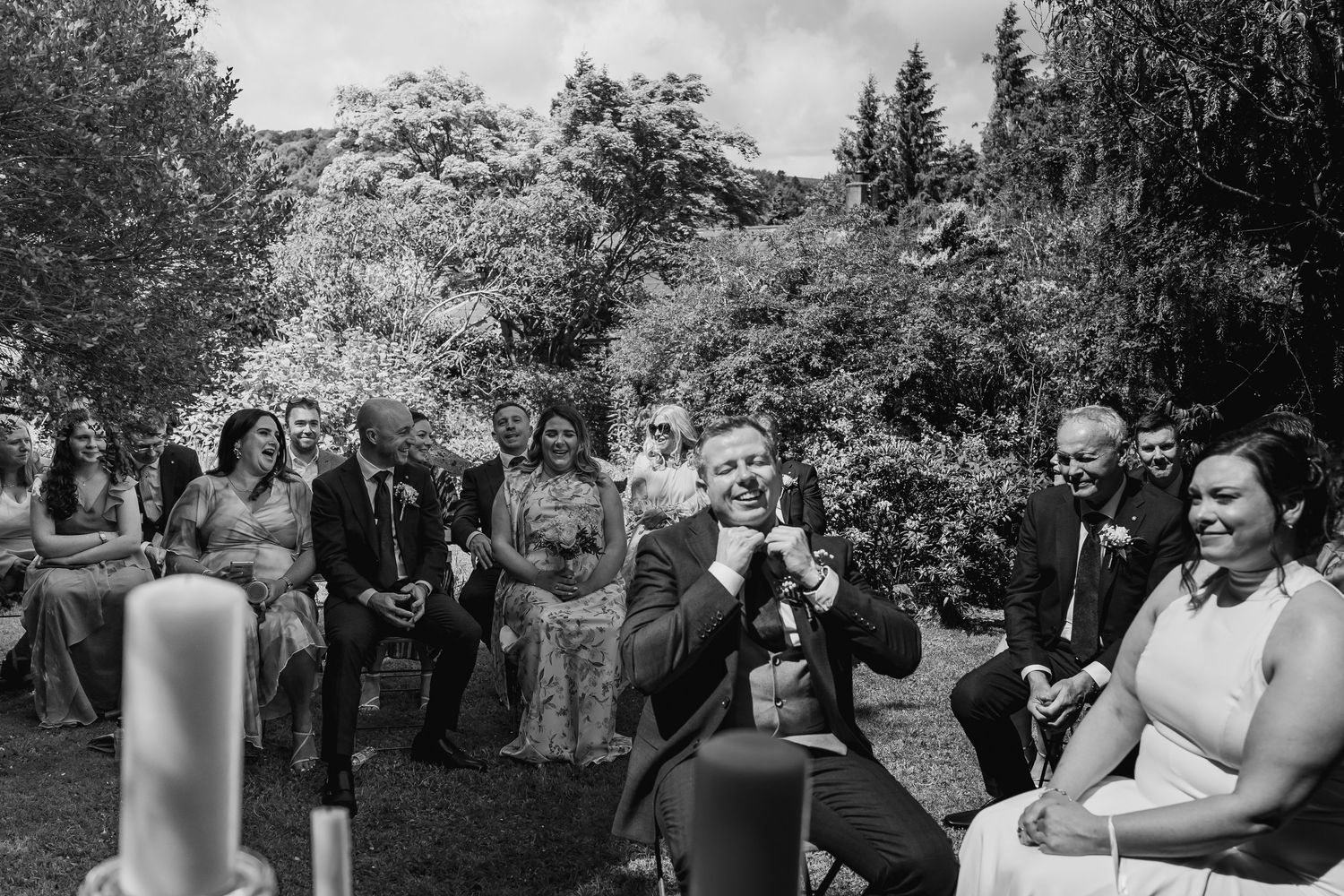 Black and white photo of bride and groom laughing during outdoor garden wedding ceremony.