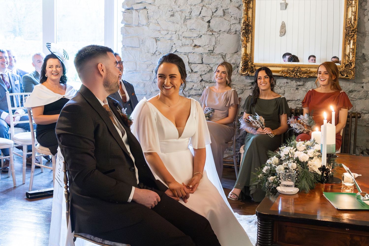 Wedding ceremony in a rustic venue with stone walls and elegant candle decorations.