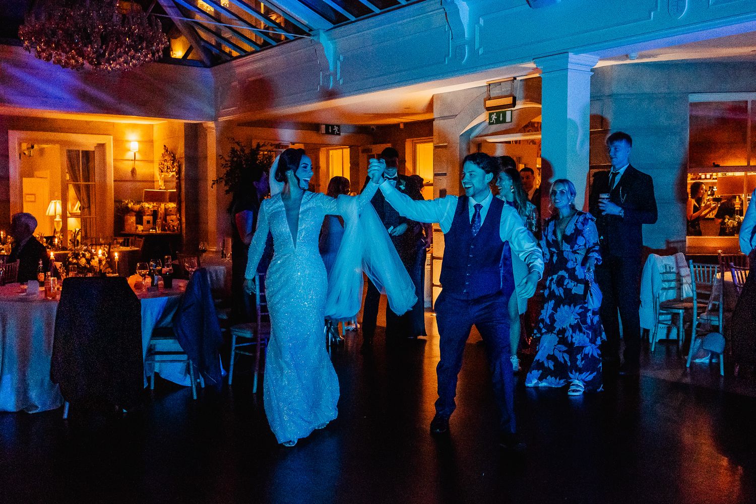 Wedding dance floor in Fallon & Byrne illuminated in dramatic blue lighting with guests celebrating.