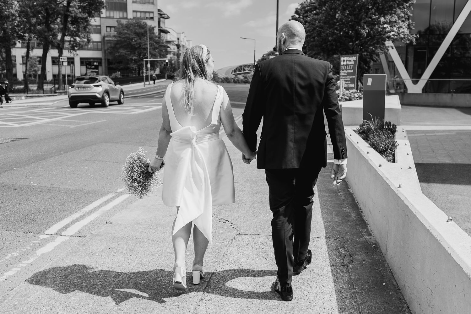 Black and white photo of wedding party walking along Dublin sidewalk.