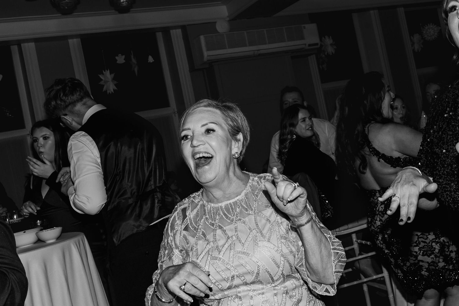 Black and white photo of guests celebrating and dancing at a wedding reception.