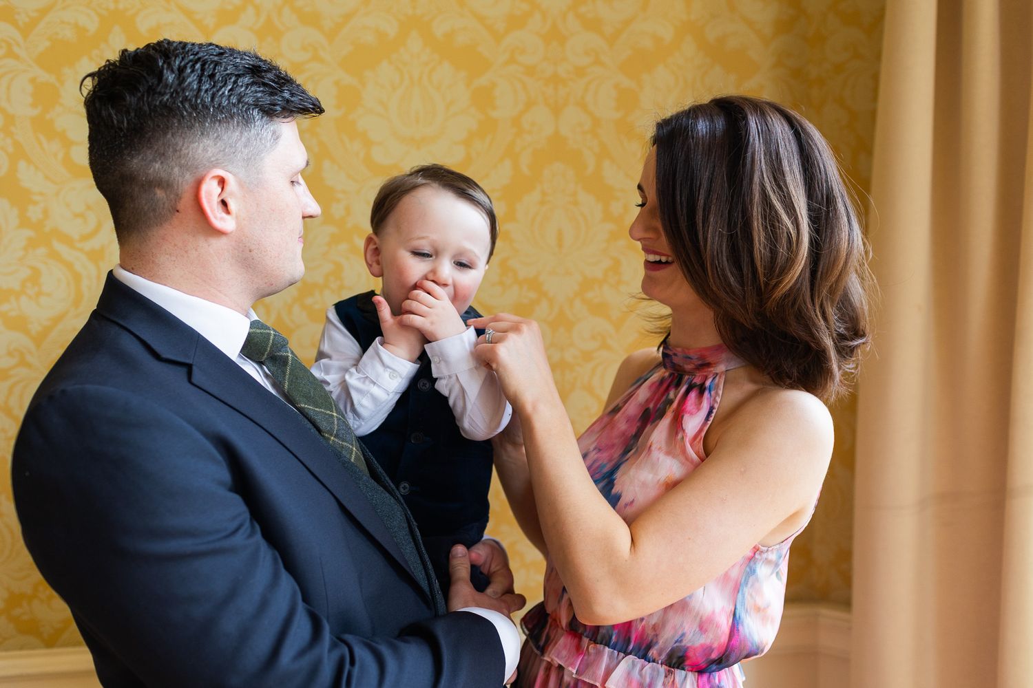 Candid Dublin wedding celebration moments photographed against yellow wallpapered interior.