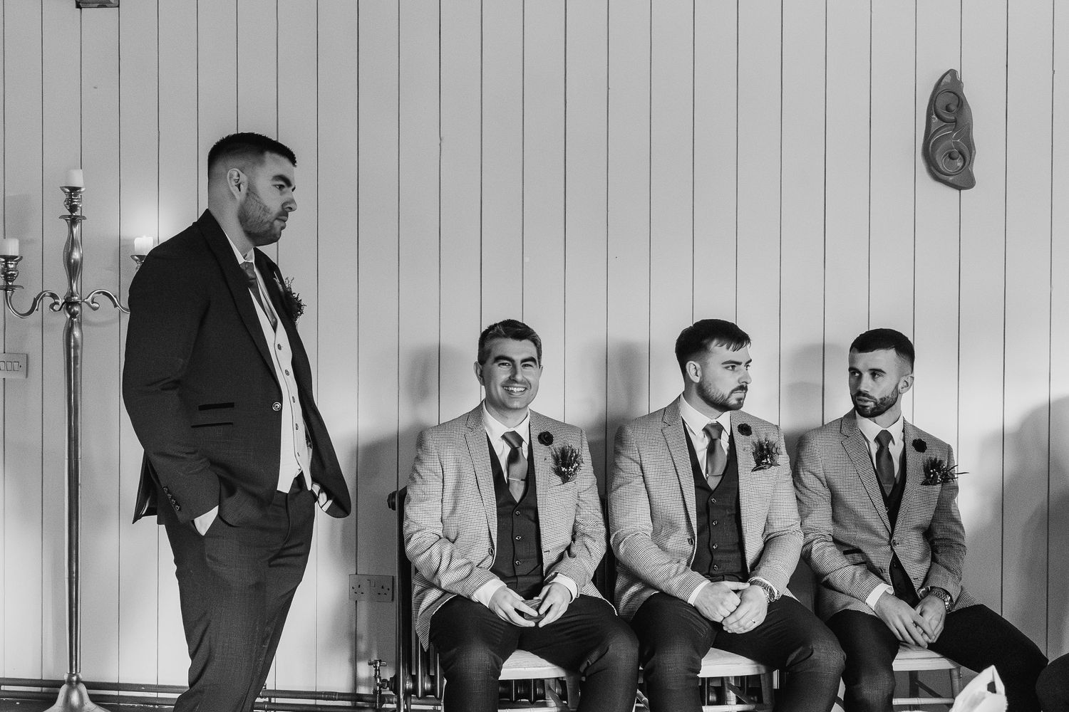 Black and white photo of groom and groomsmen in suits waiting before wedding ceremony.