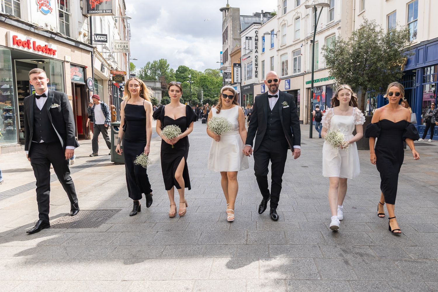 Group walking down a Dublin city street in formal wedding attire unposed, relaxed and happy wedding photography.