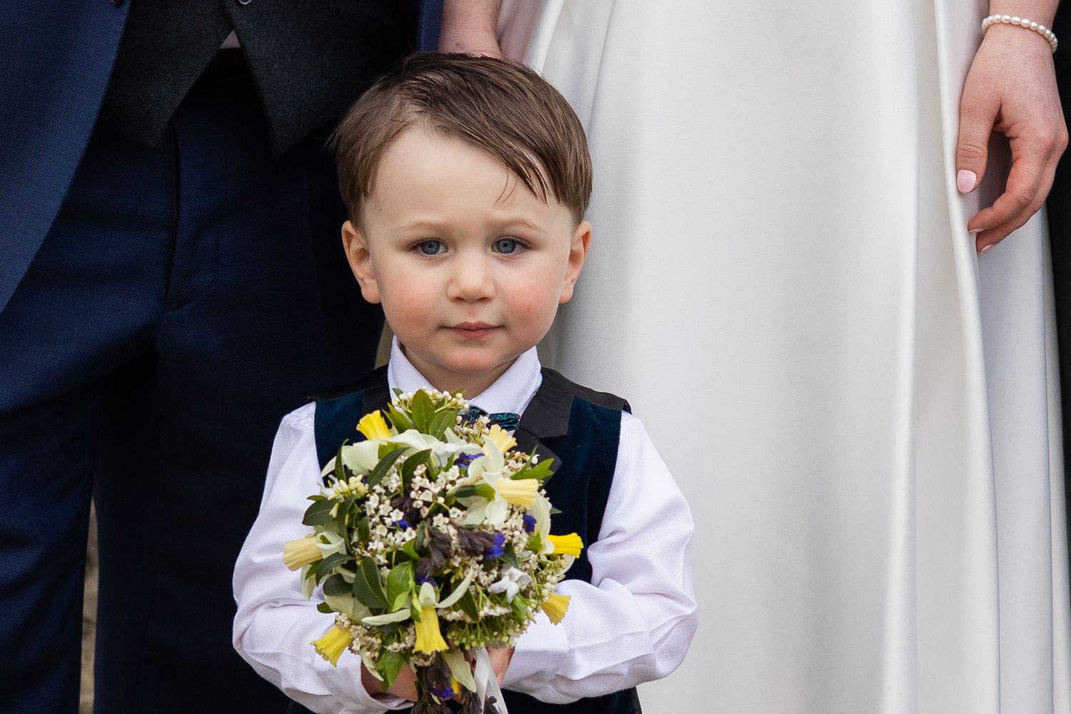 Young attendant in formal wear holding a floral bouquet at a Dublin city wedding ceremony.