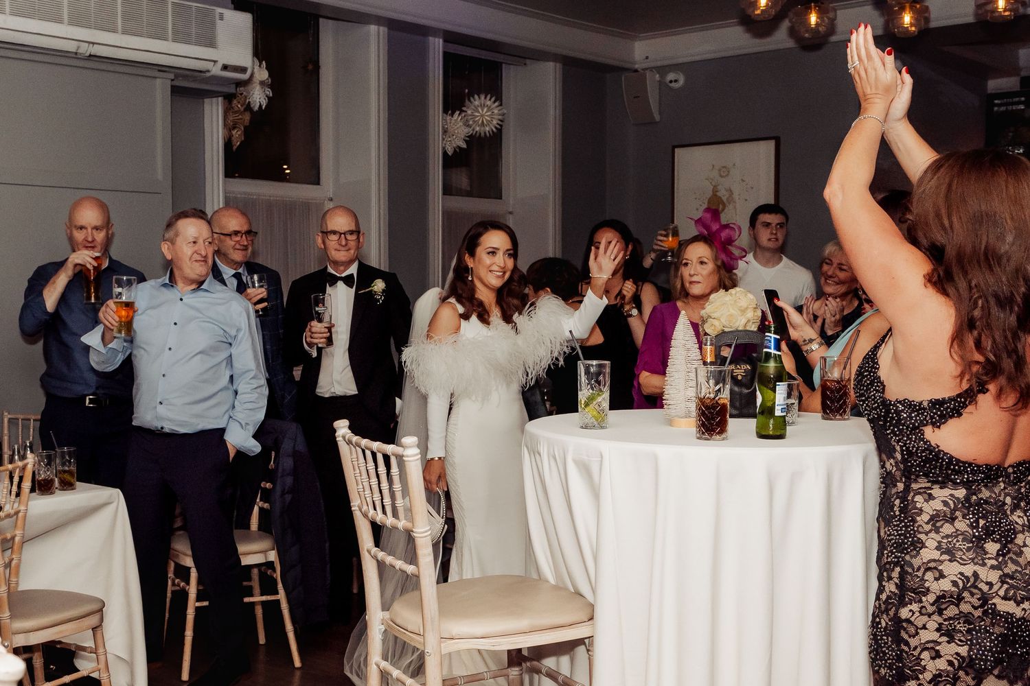 Wedding guests mingling and socializing at tables during evening reception.