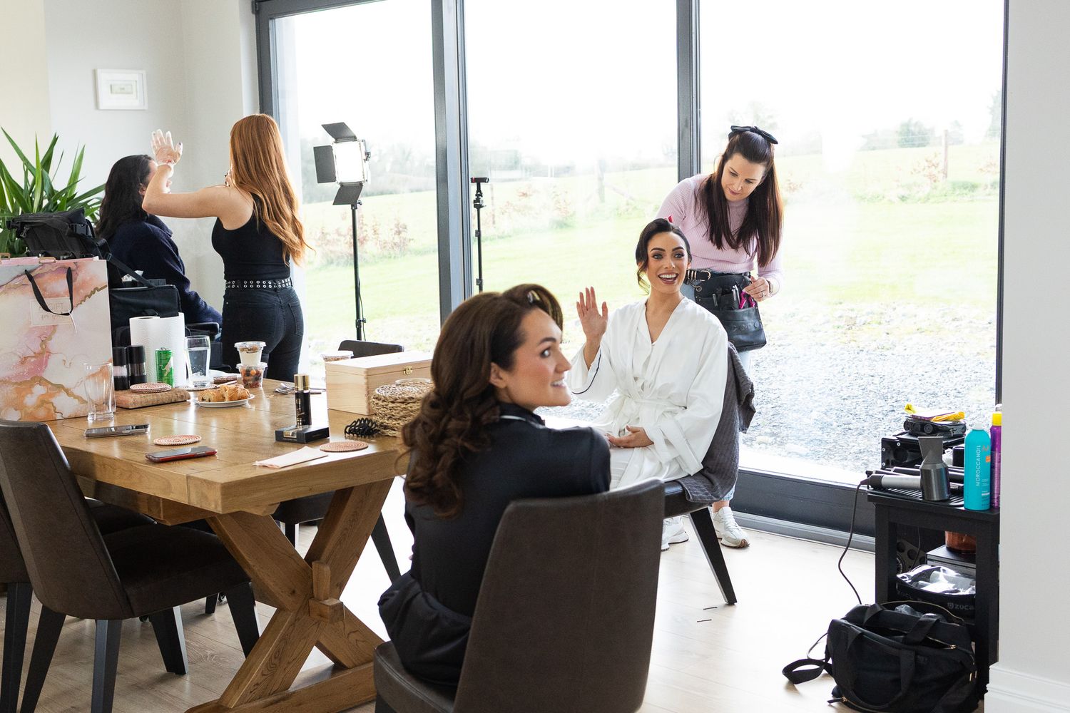 Behind the scenes of wedding preparation with makeup artists and cameras in bright room photo by Dublin wedding photographer.