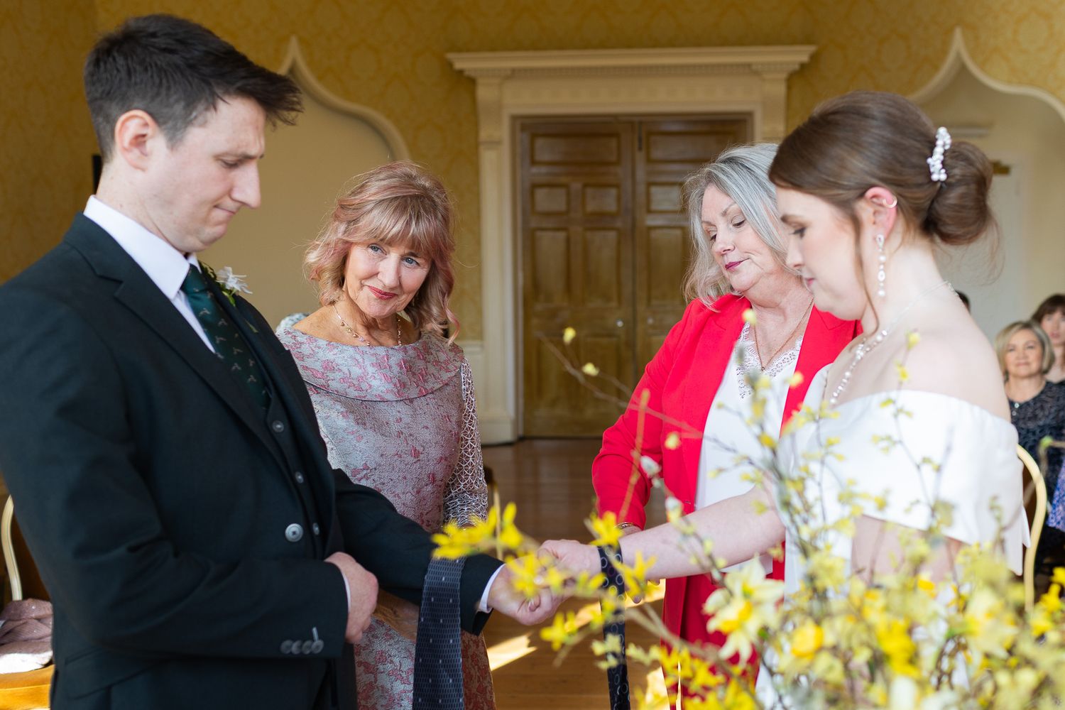Wedding party during intimate Dublin wedding ceremony in MoLI, with yellow floral arrangements and warm lighting.