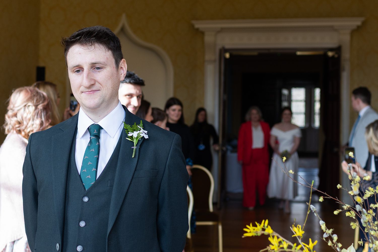 Wedding party members gather in formal attire inside Dublin's MoLI  with sunlit windows.