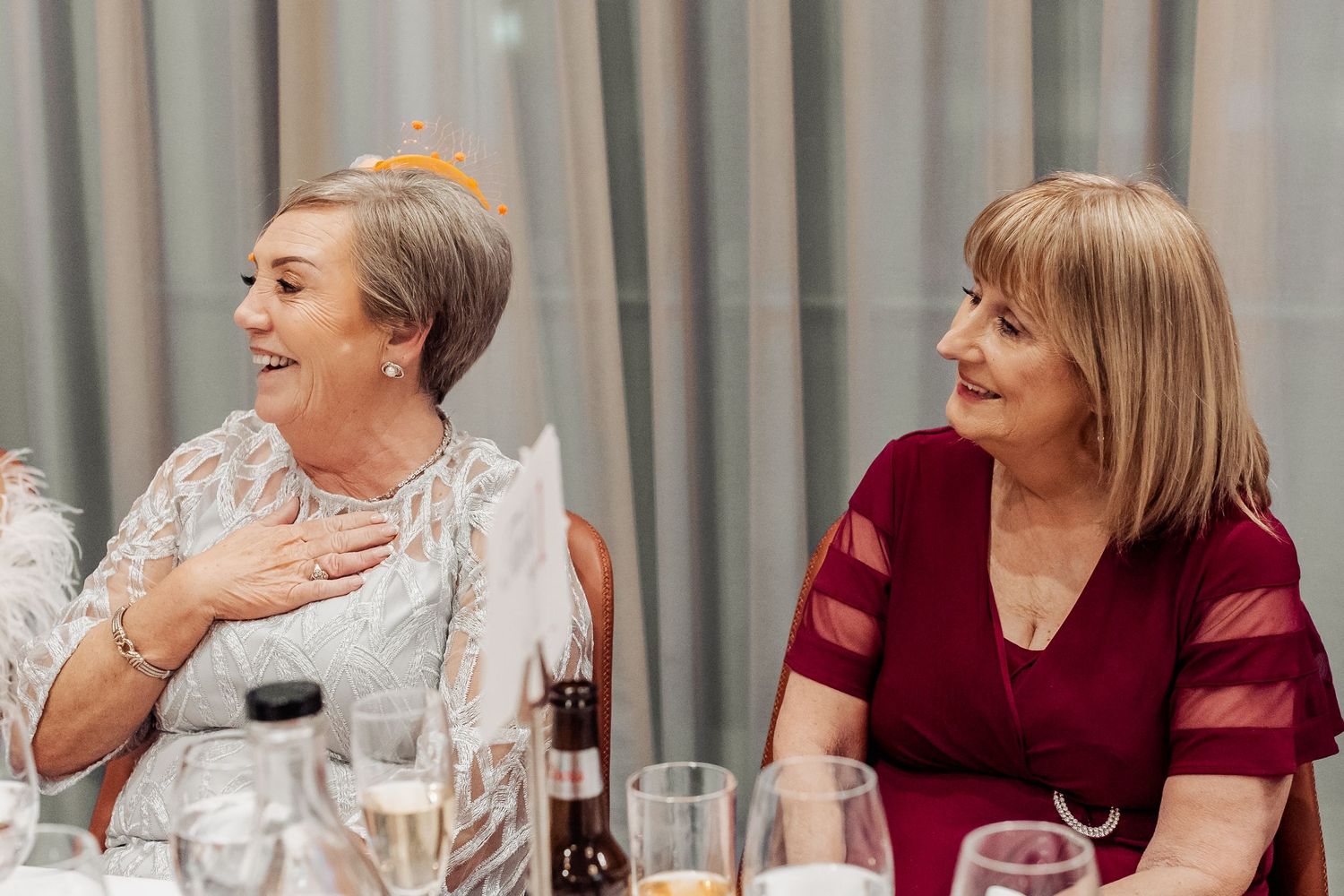 Wedding party members seated at a table having animated conversations.