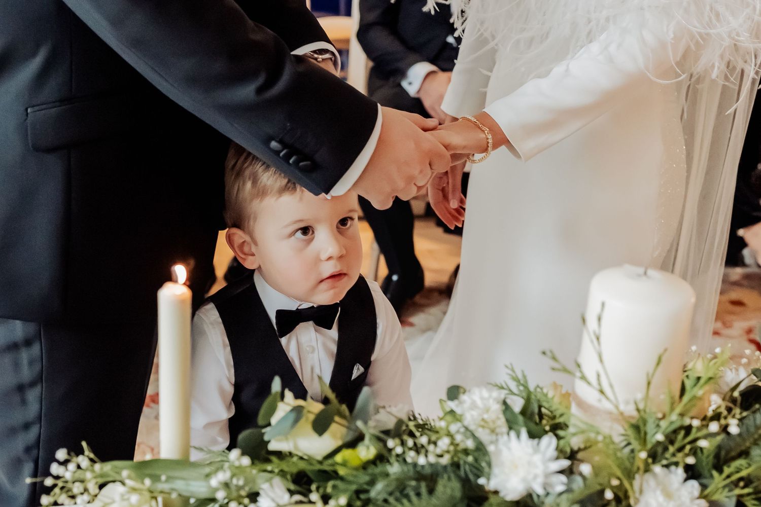 Wedding reception details featuring elegant table settings with greenery and white candles.