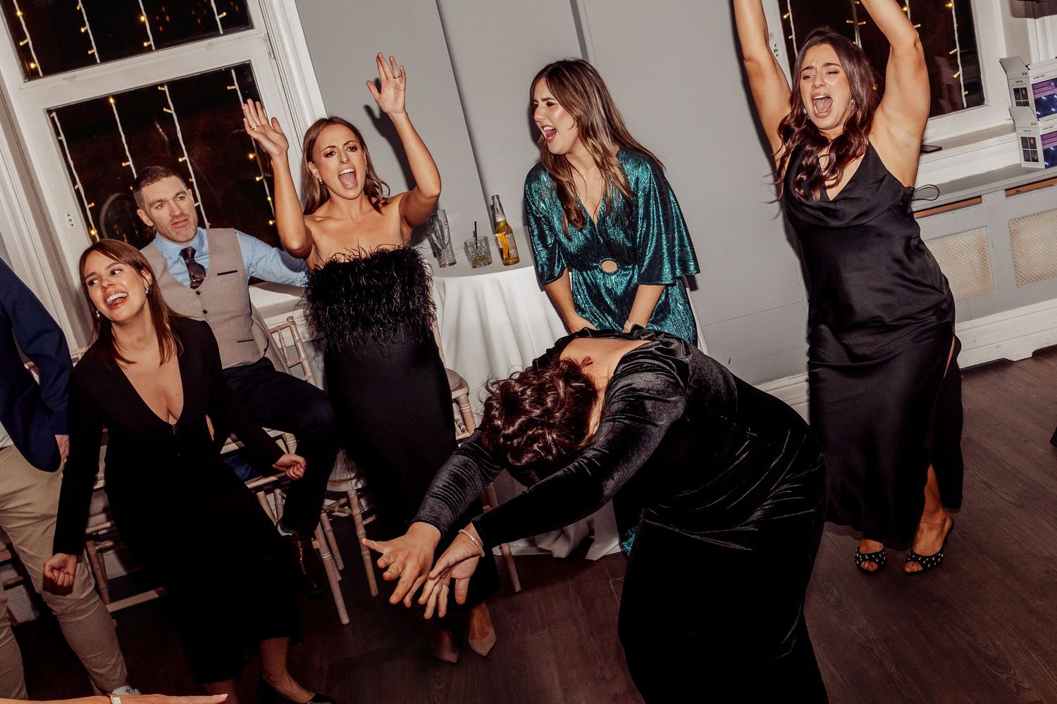 Wedding guests dancing and having fun on dimly lit dance floor.