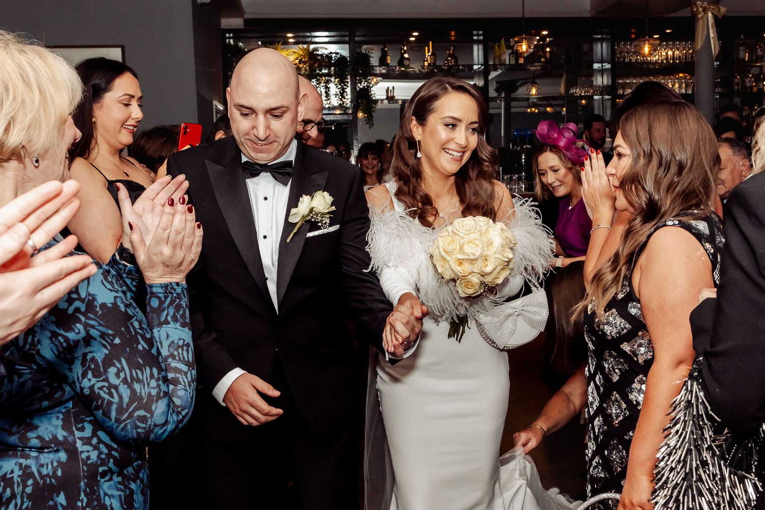 Wedding reception party with guests dancing and celebrating on a dark dance floor.