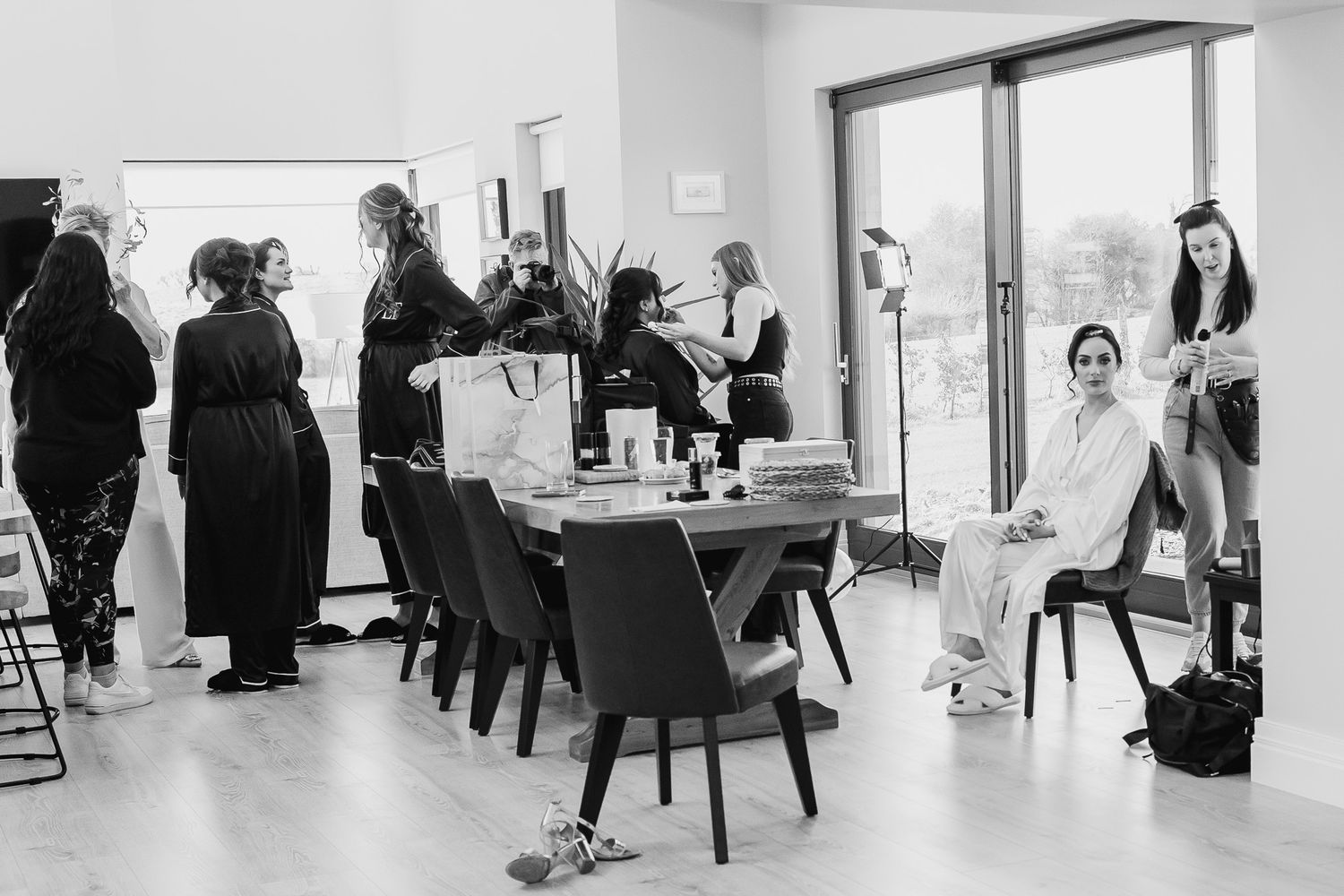 Black and white photo of wedding morning preparations in modern dining room setting.