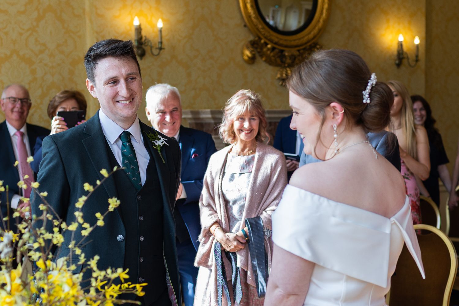 Dublin wedding reception with guests socializing in a MoLI  room with gold walls and chandeliers.