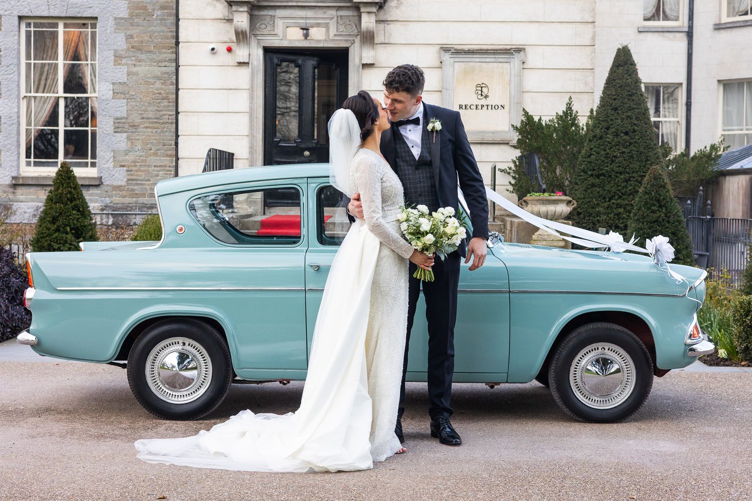 Wedding couple poses for Dublin city weddings photographer with a classic mint green vintage car outside Tankardstown.