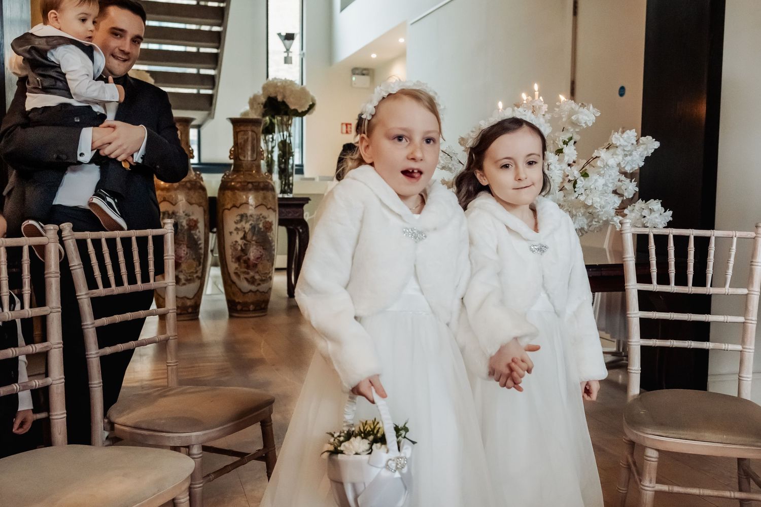 Young children in white formal attire playing during a wedding reception.