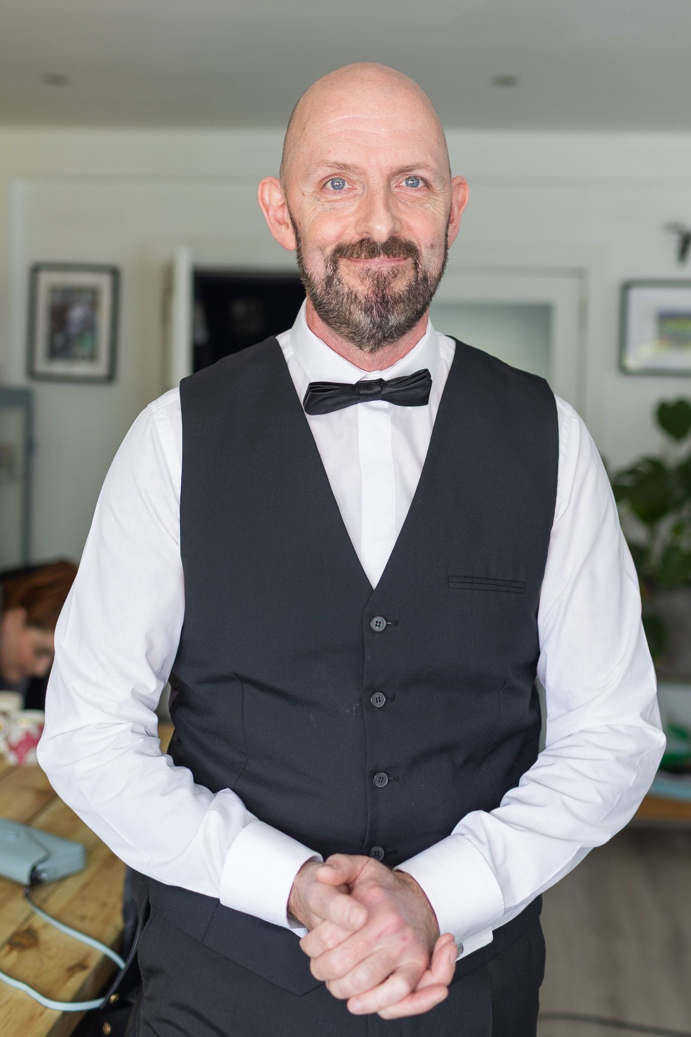 Groom in formal attire with white shirt and black vest posing in Dublin registry office setting.