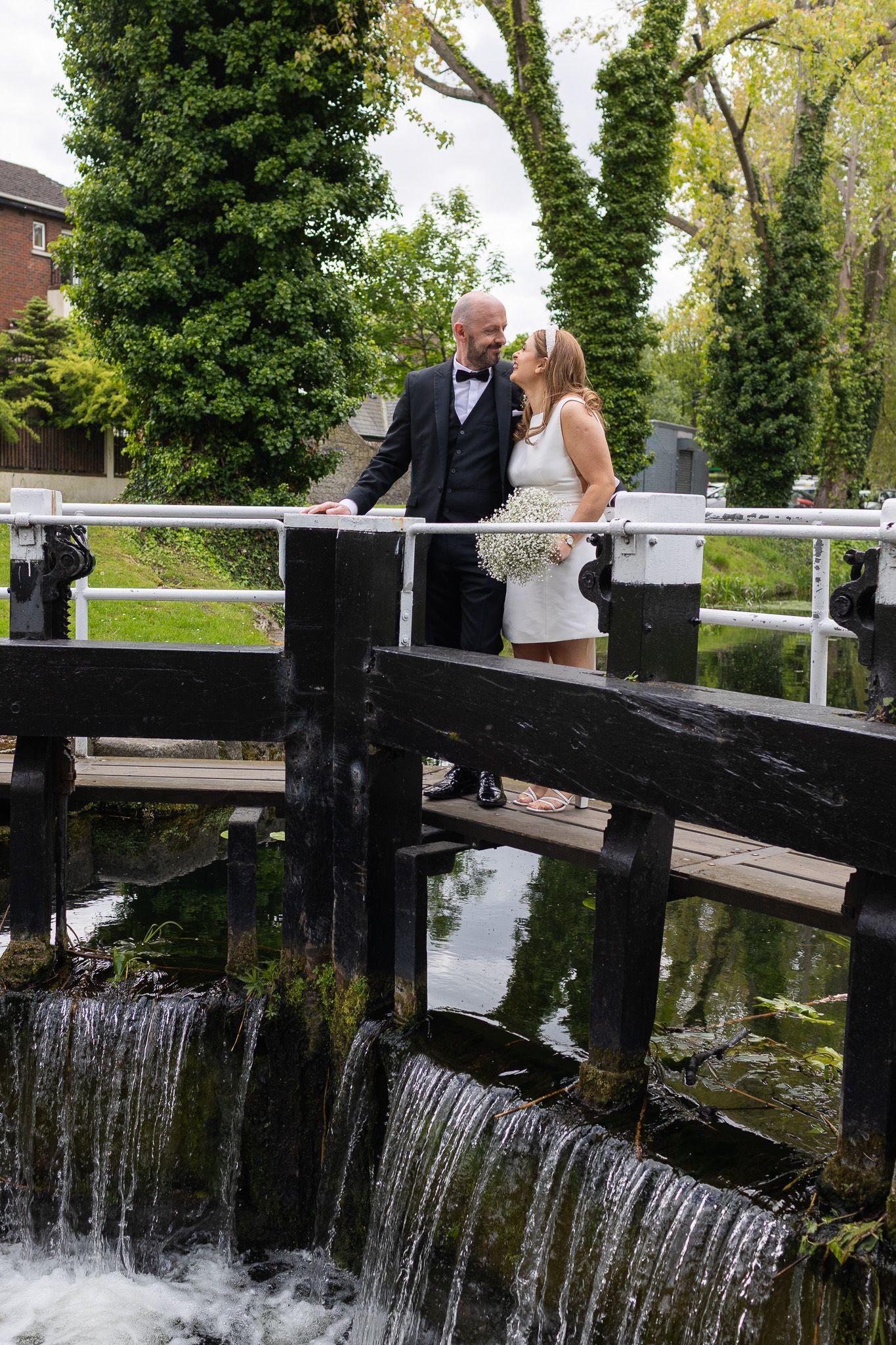Couple poses on a wooden bridge over a cascading waterfall after their Dublin CIty Registry office wedding.