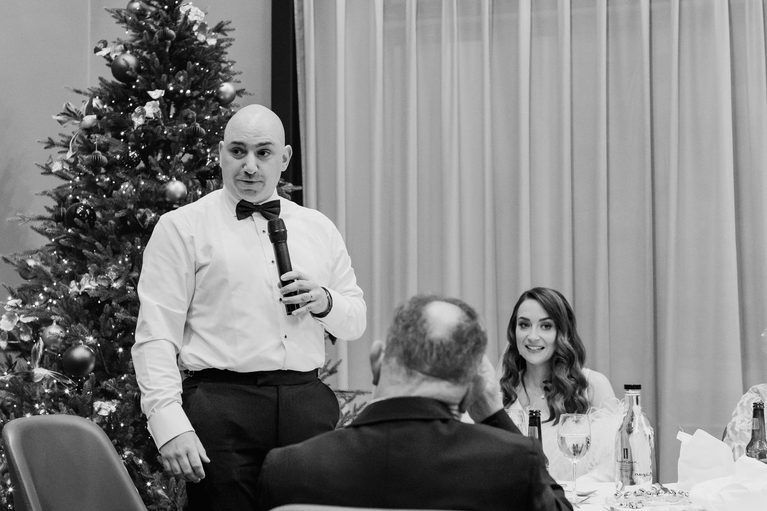 Wedding reception venue with Christmas trees and white curtains creating an elegant atmosphere.