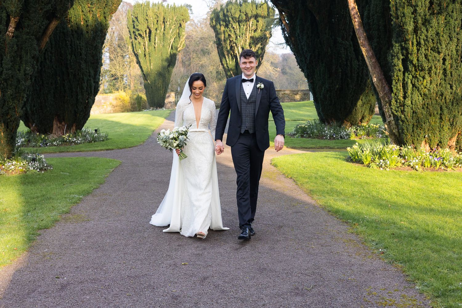 Newlyweds strolling through scenic garden grounds on their wedding day, no fuss wedding photos by Dublin wedding photograpraphy.