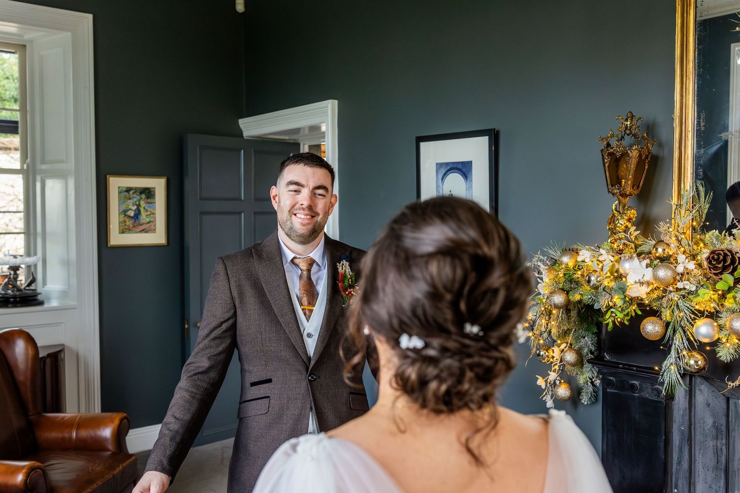 A couple shares a special moment in an elegant room with dark green walls.