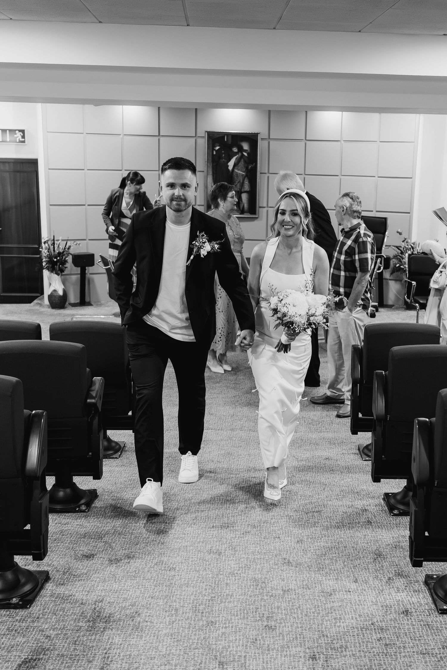 Black and white photo of a bride and groom walking down the aisle after their wedding ceremony.