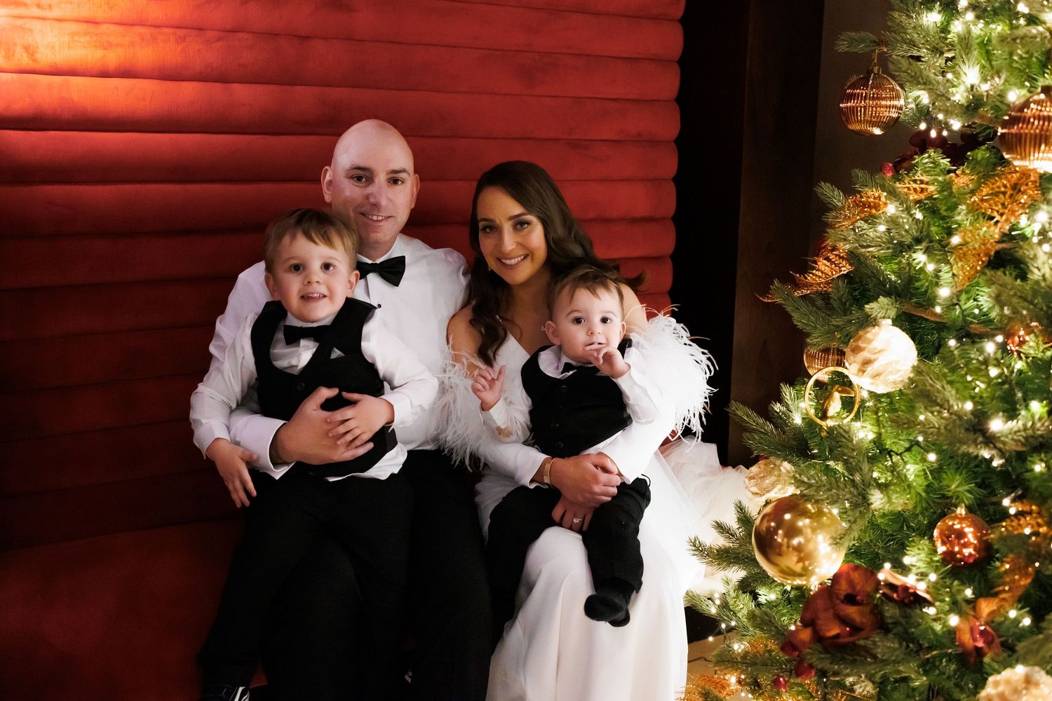 Family portrait session in front of red barn with Christmas lights and decorations.