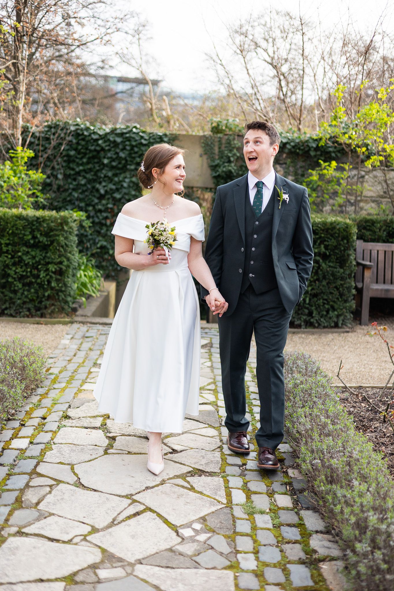 Newlyweds share laughs while walking along a stone garden path surrounded by greenery in Dublin CIty centre.