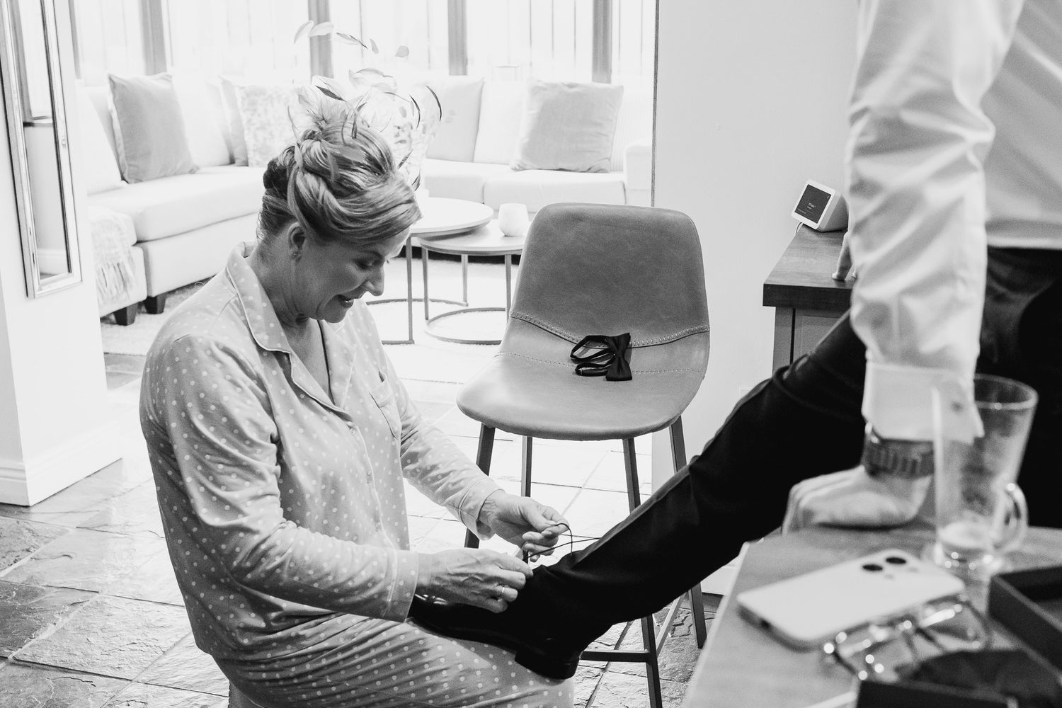 A person in formal attire polishes a shoe during wedding preparations.