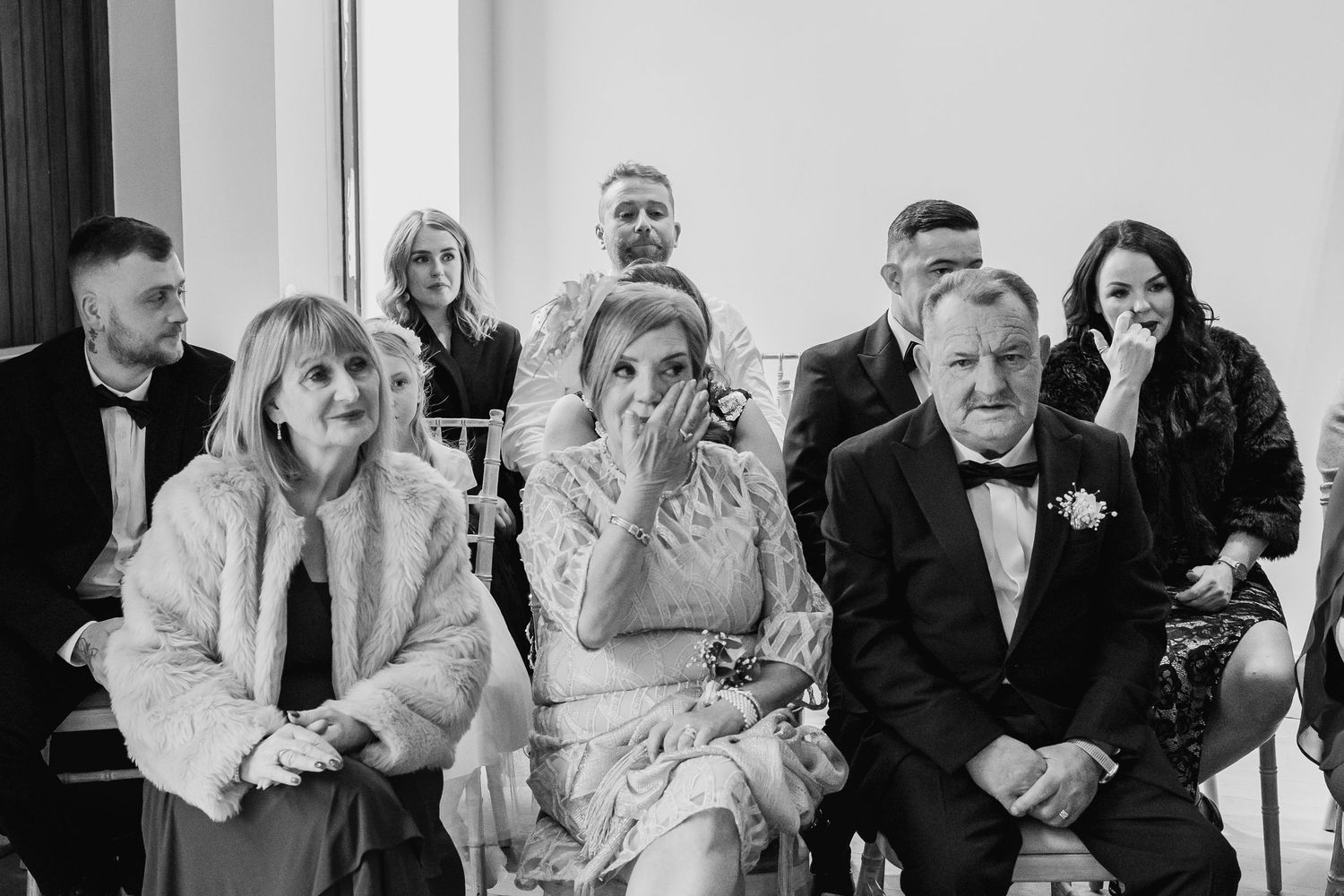 Wedding guests laugh and celebrate during a joyous reception moment.