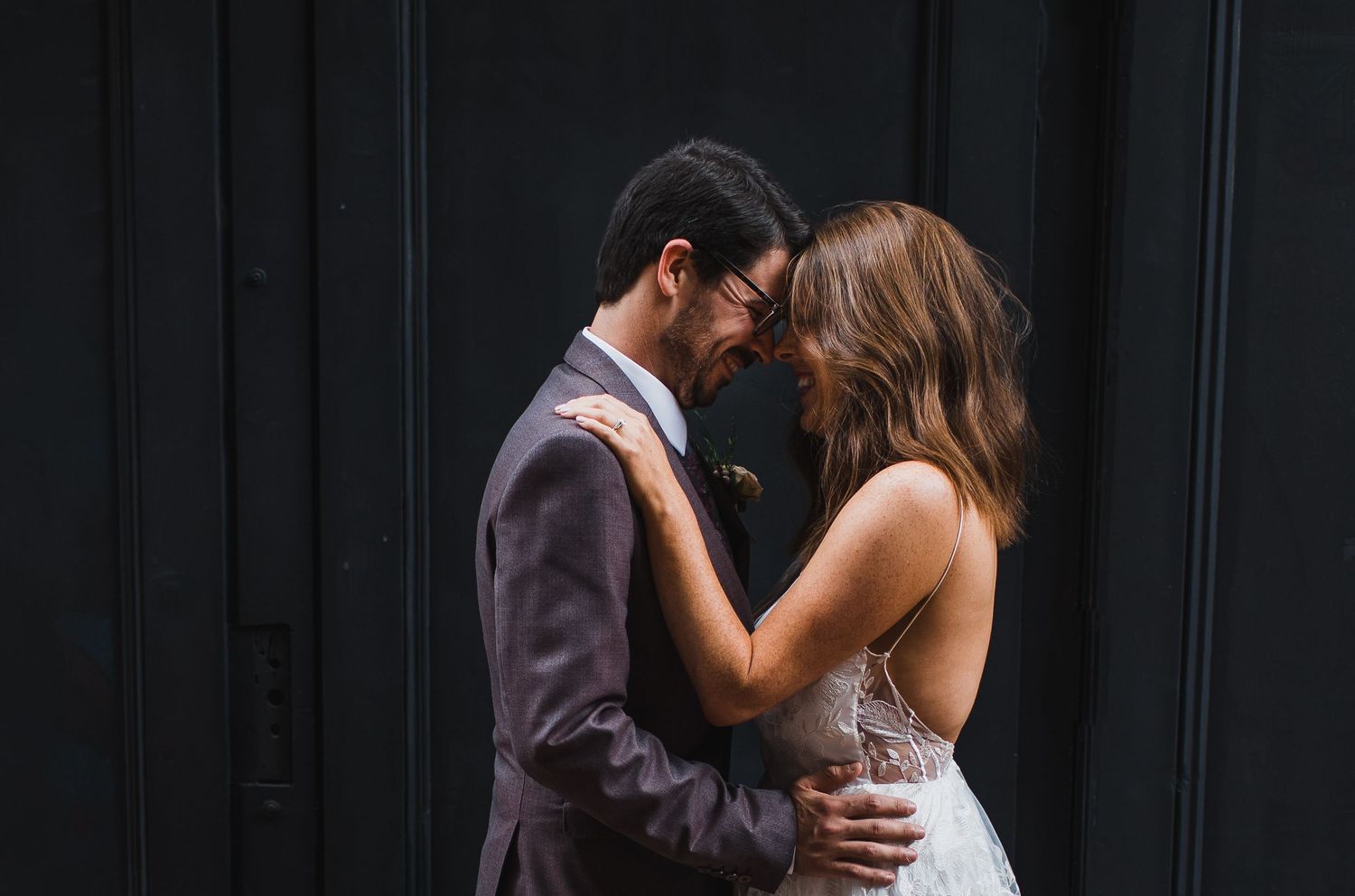Romantic couple embraces against a dark wooden wall background.