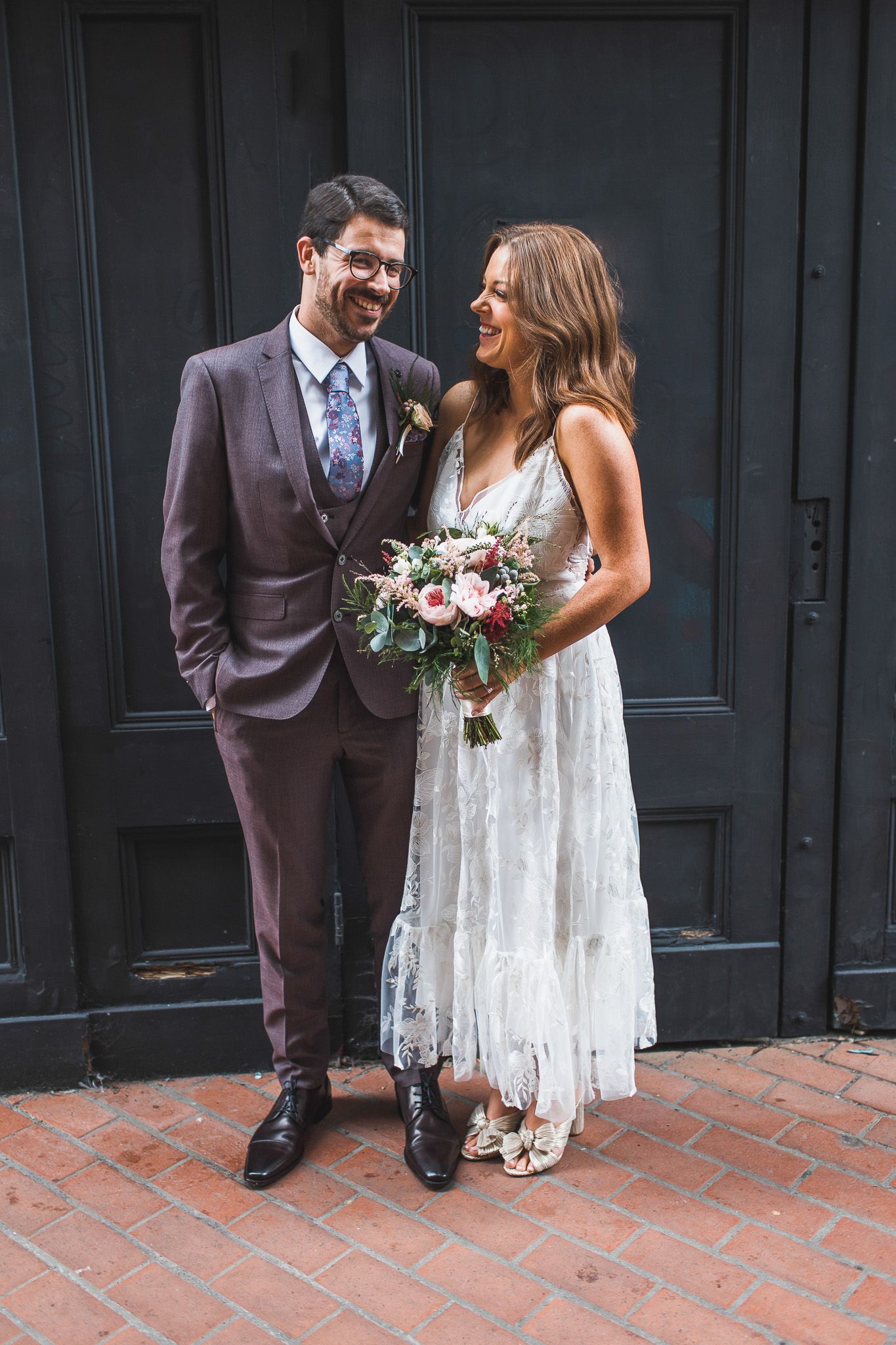 A couple shares an intimate moment against dark doors on their wedding day.