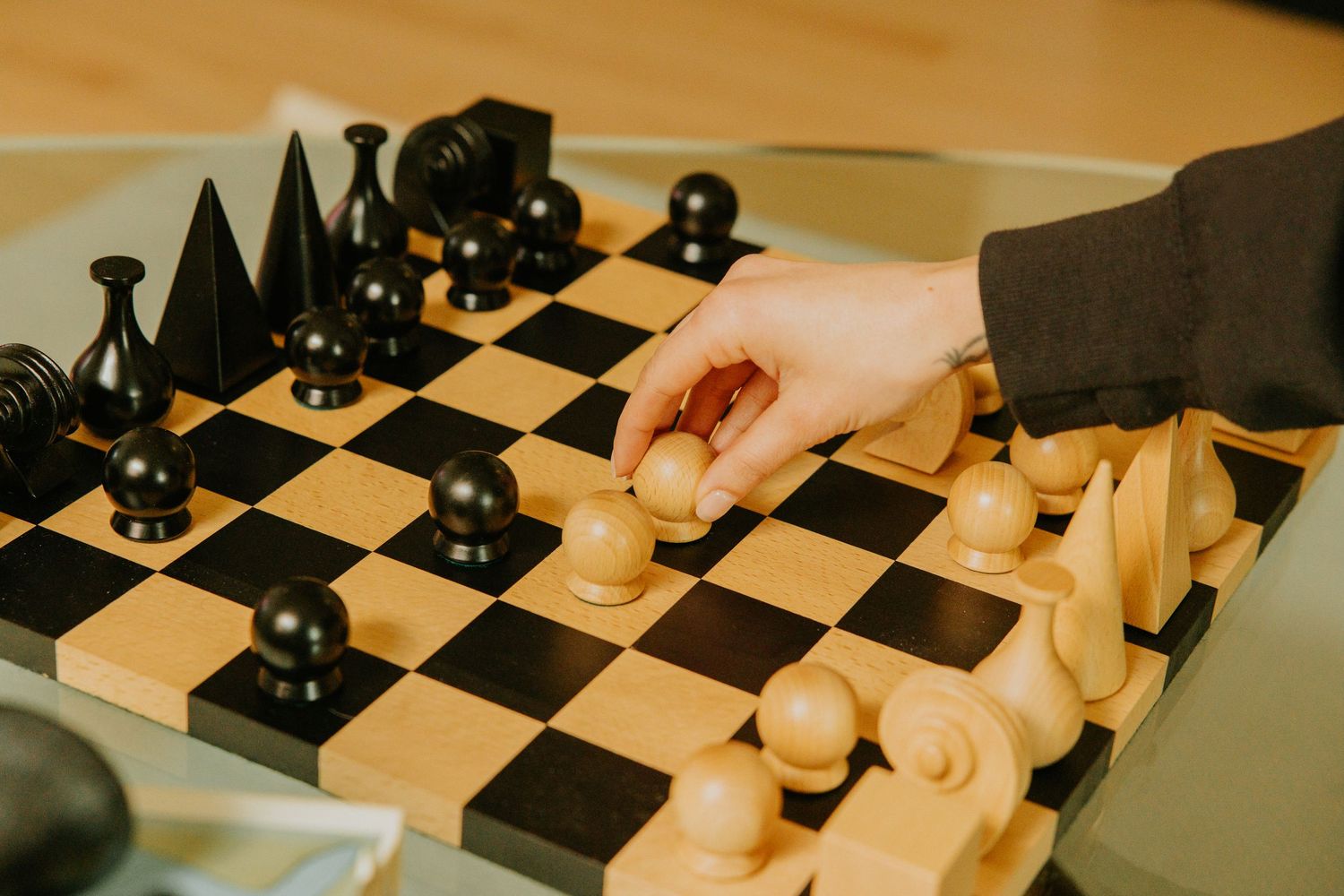 Woman moving a pawn on a chess set, shot by Dylan Spangler