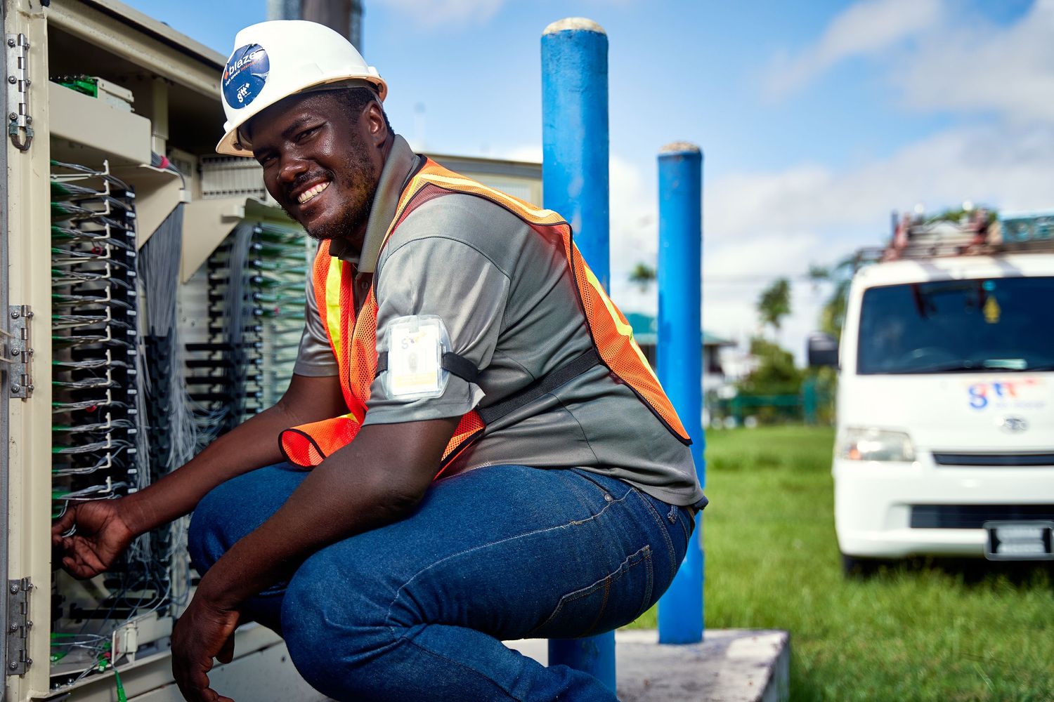 HVAC technician in gray uniform and orange gloves performing maintenance on an outdoor air conditioning unit.