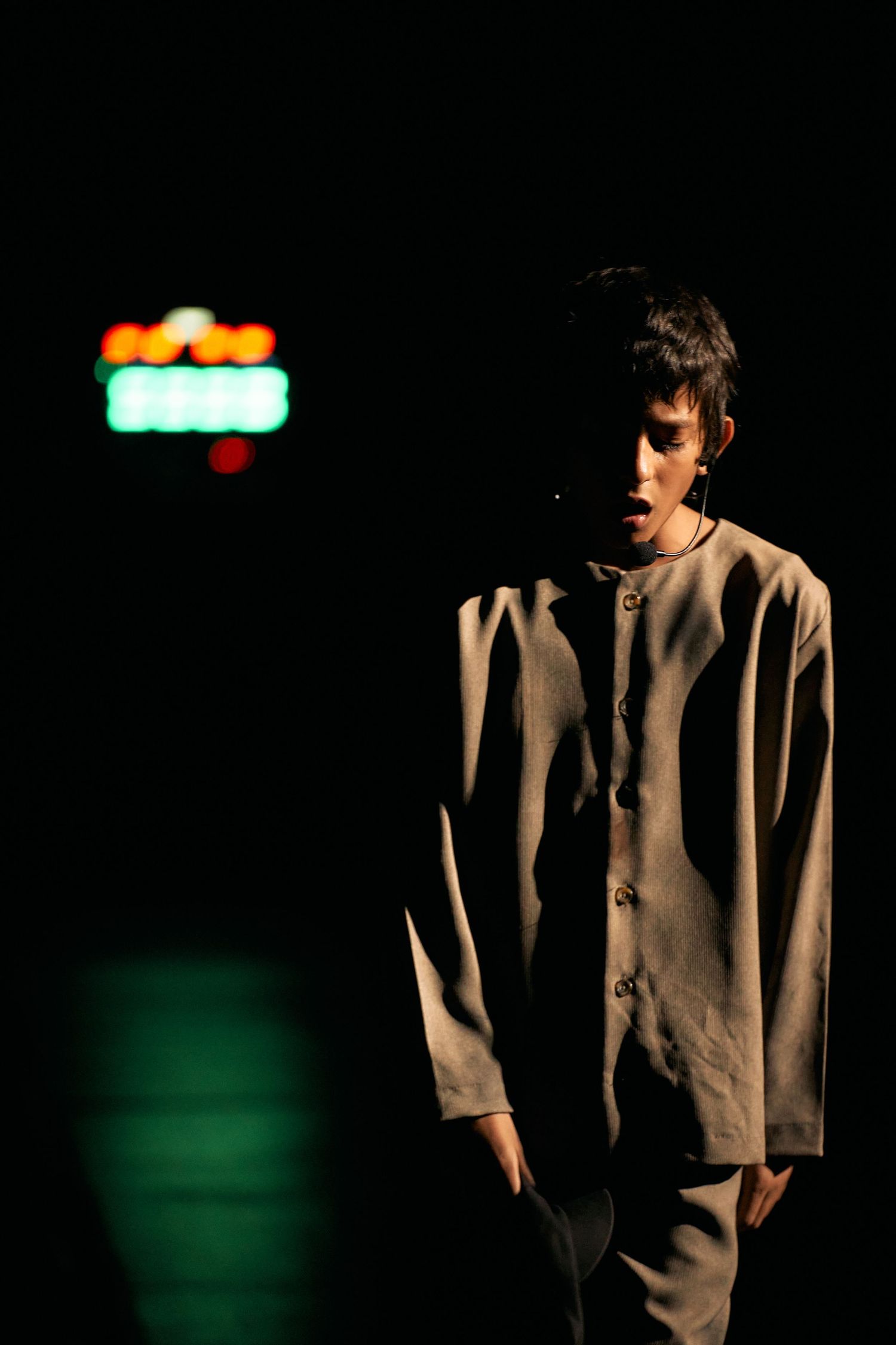 Dramatic portrait series showing a person in low light wearing a beige jacket against dark background with green accents.