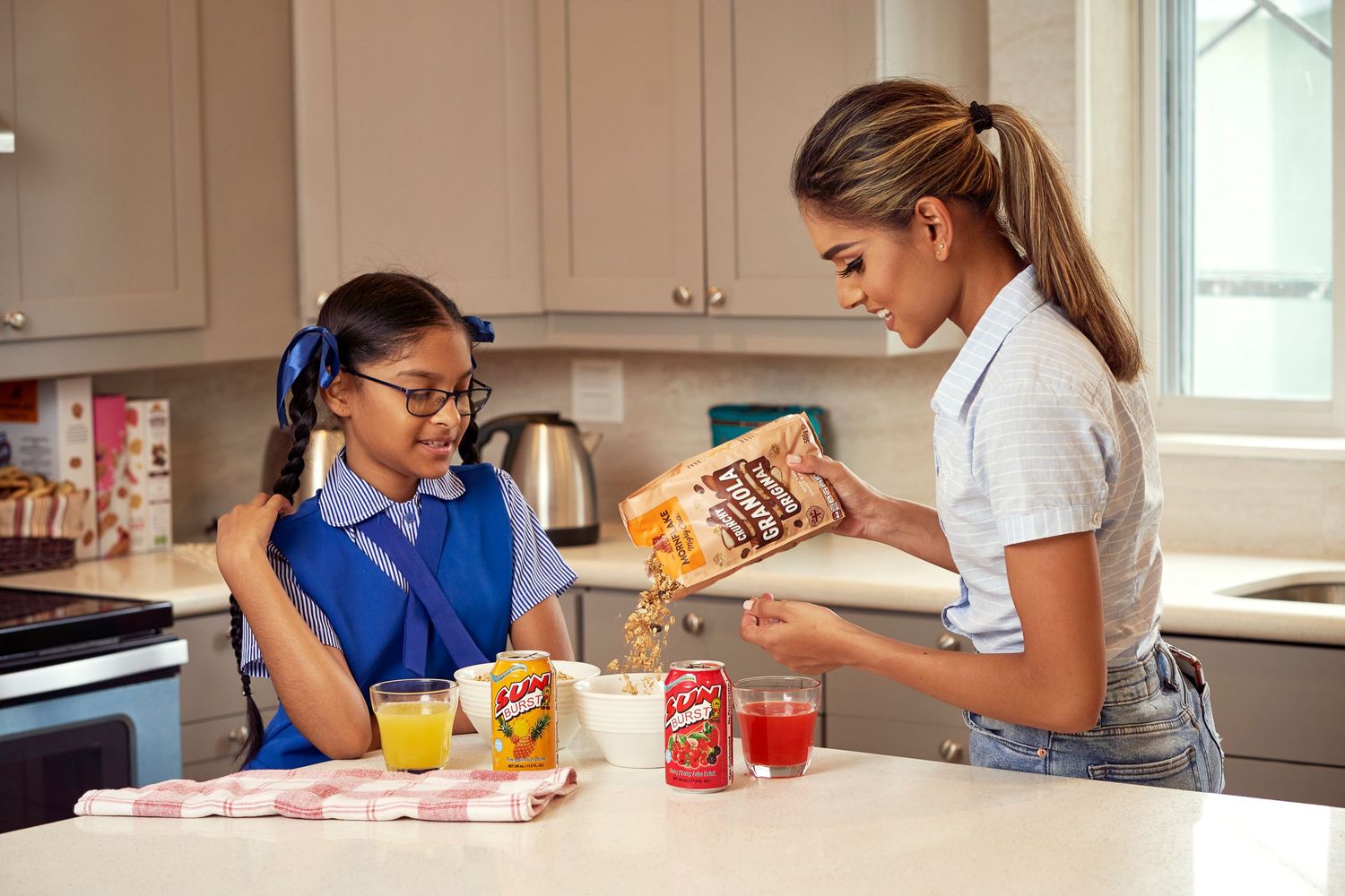 Four people prepare food together in a bright white kitchen with natural lighting.