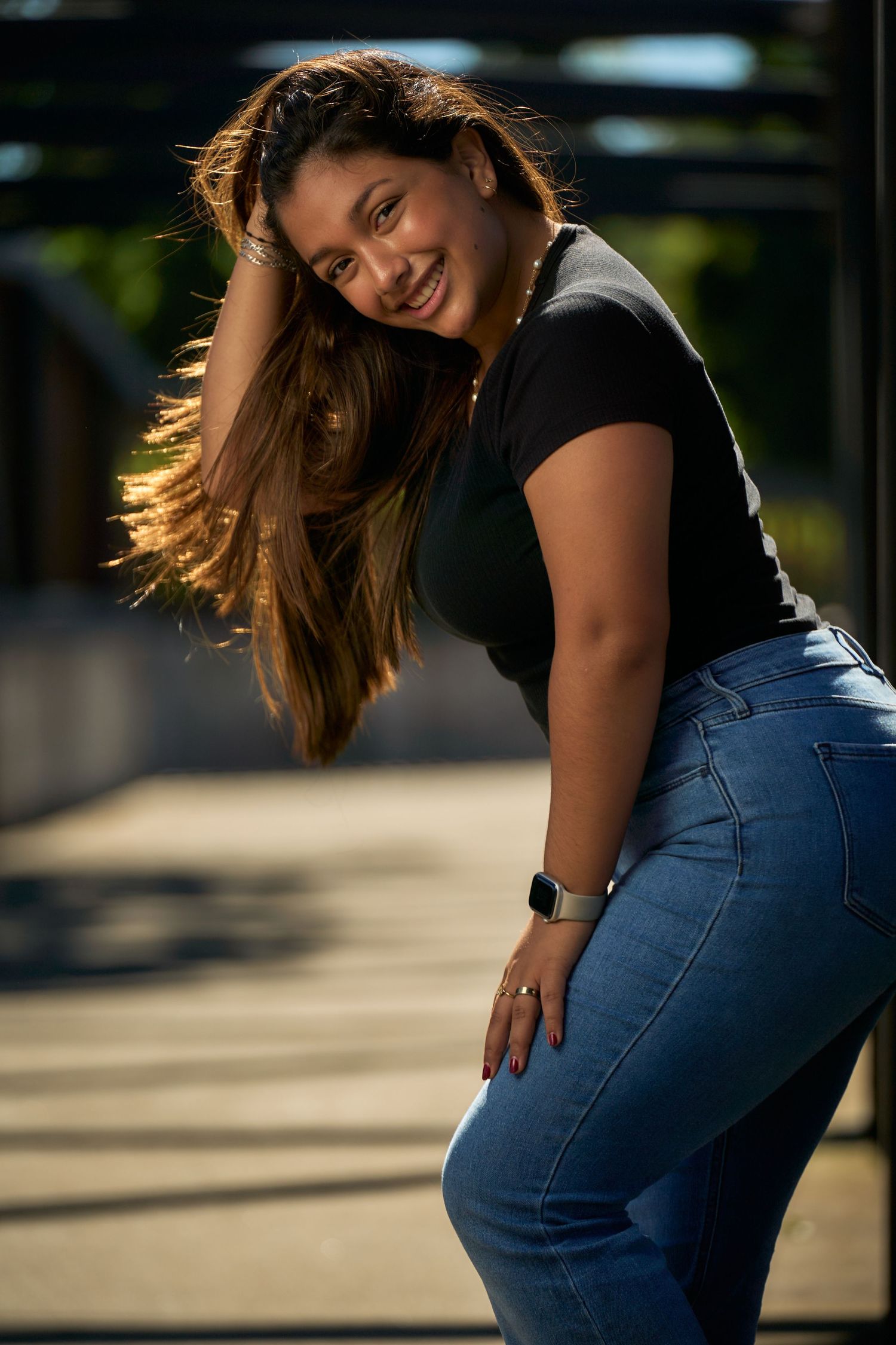 A person in casual attire poses playfully in an outdoor urban setting.