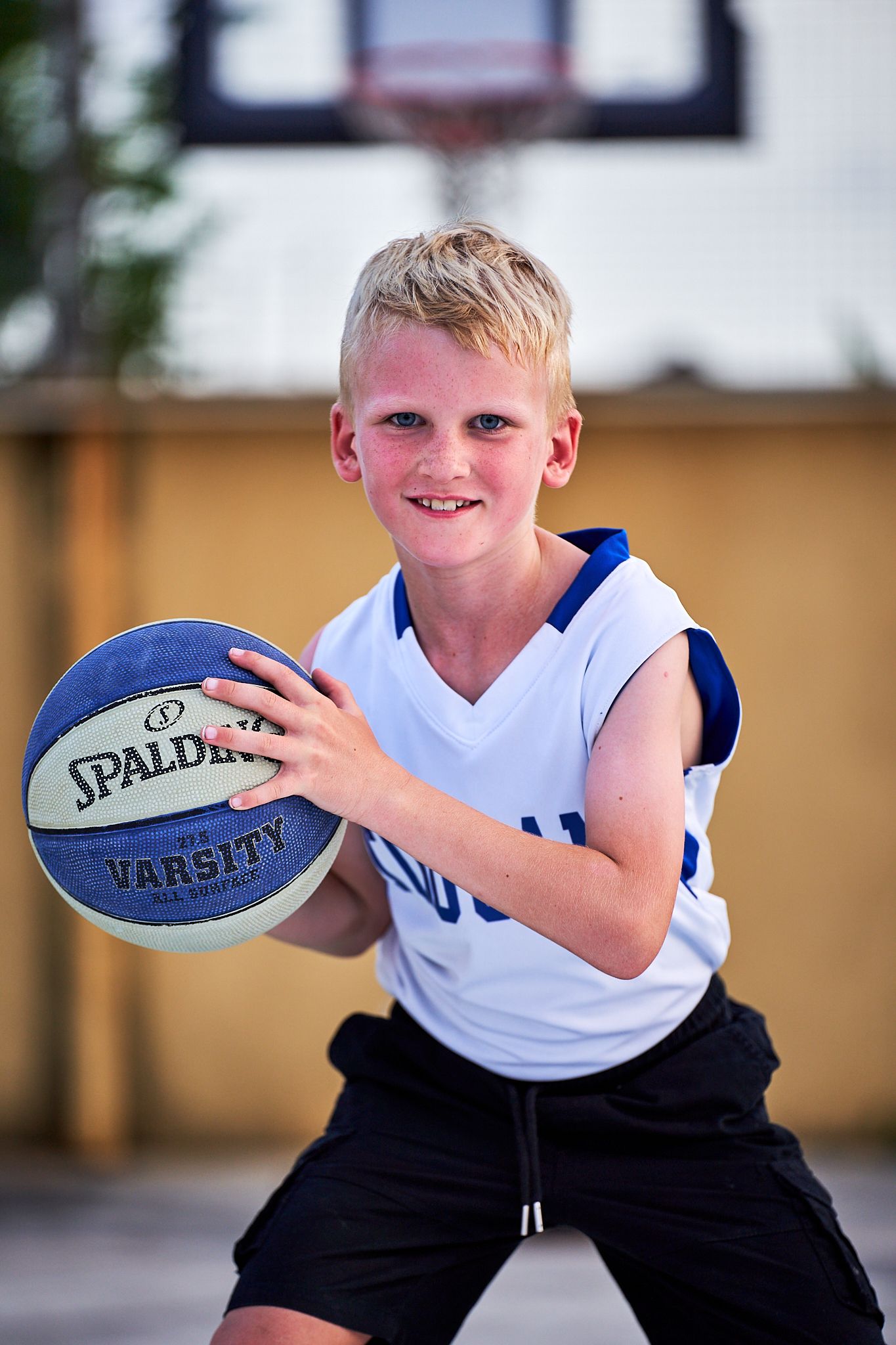 Action shots of young athlete playing with a Spalding basketball in white jersey.