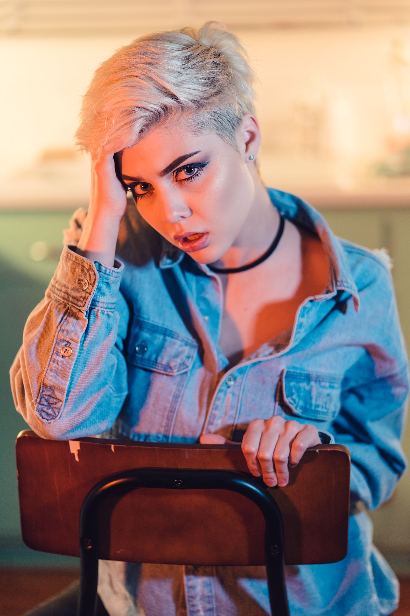 Fashion portrait in denim jacket with dramatic lighting and moody poses against wooden furniture.