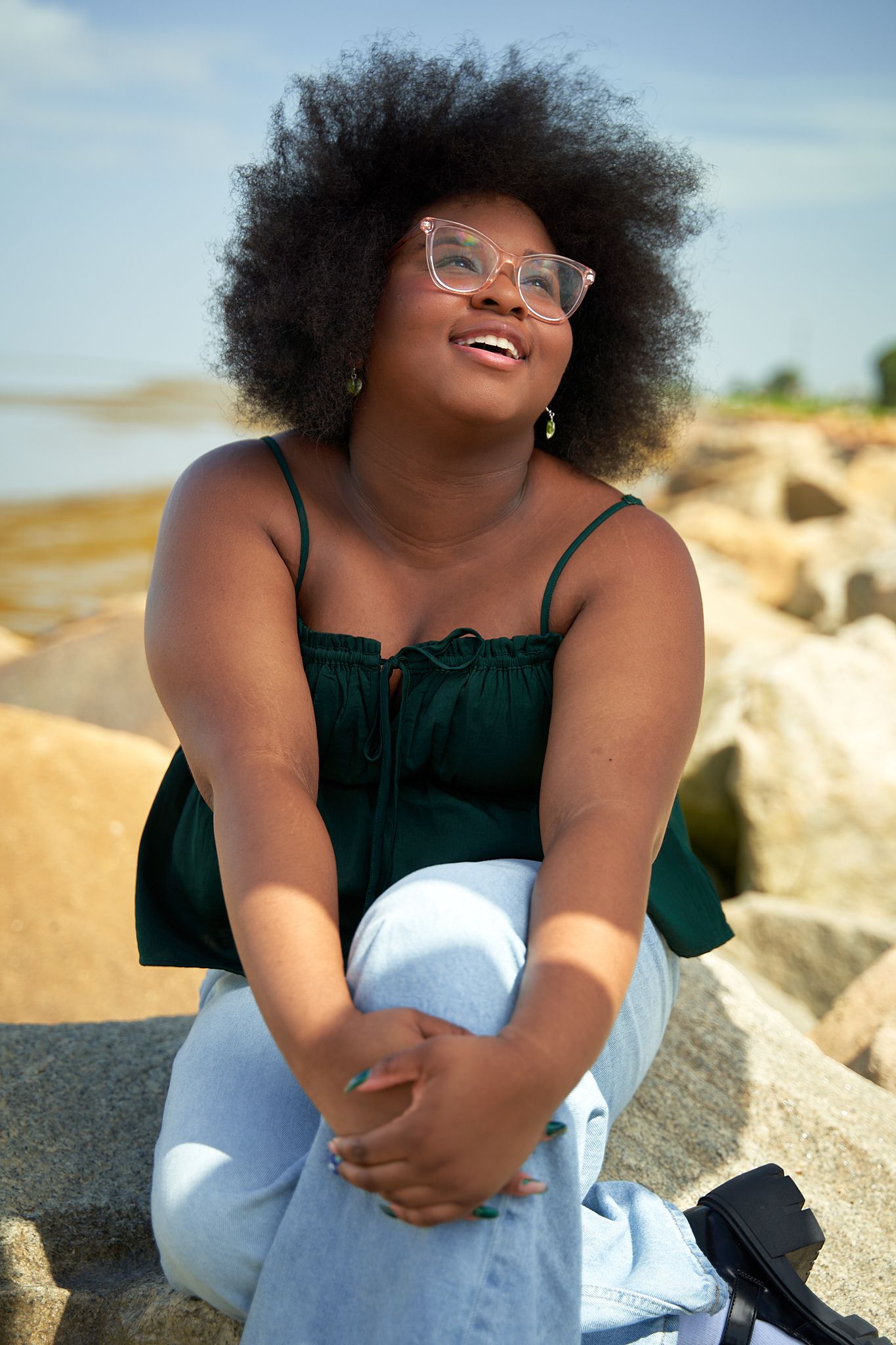 Joyful outdoor photoshoot on rocky terrain wearing casual white and black outfit.