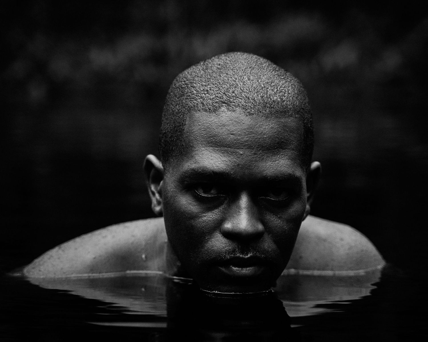 A dramatic black and white photo series shows a figure emerging from dark water in different stages.