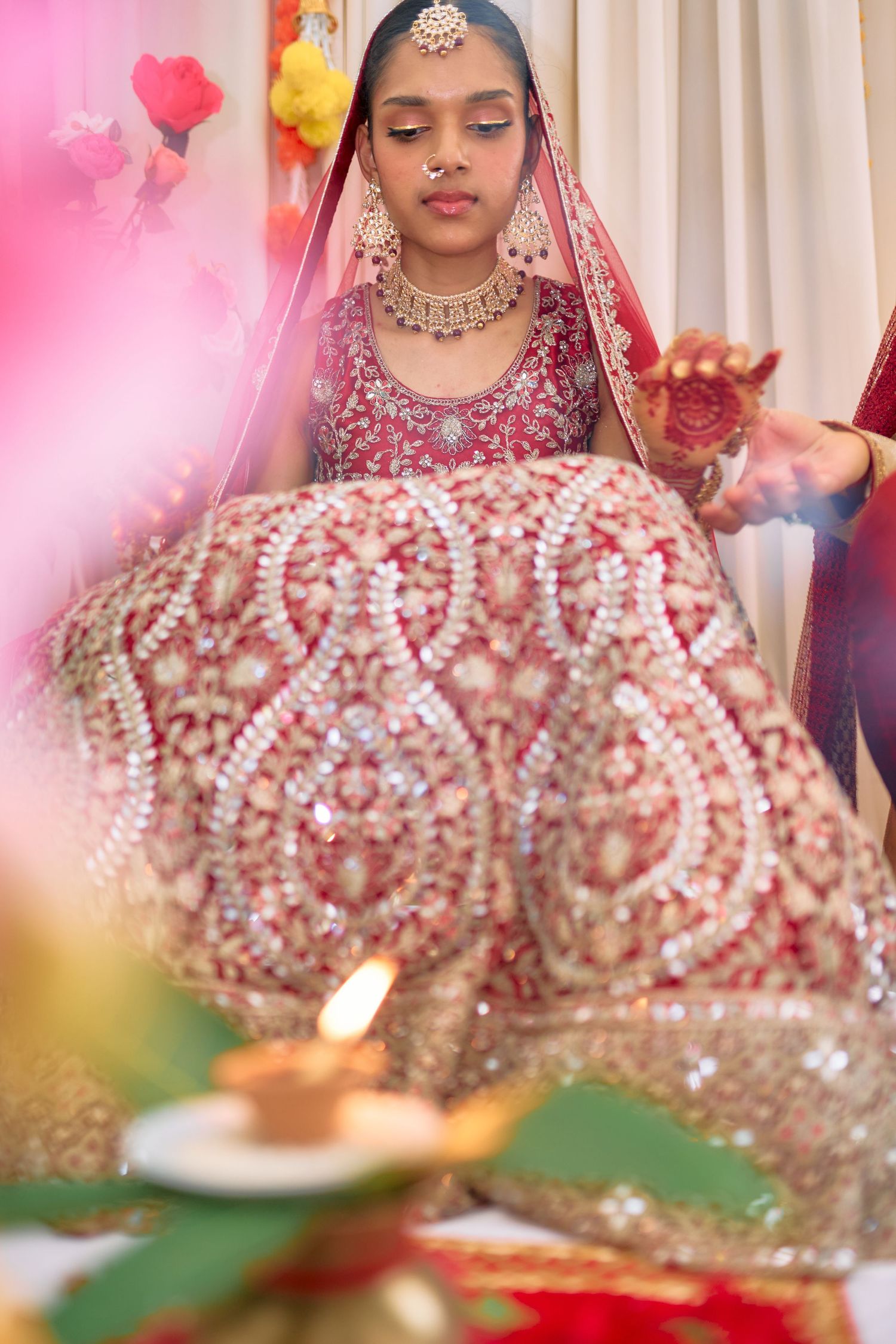 Detailed shots of intricate beadwork and embellishments on a red bridal lehenga during ceremony.