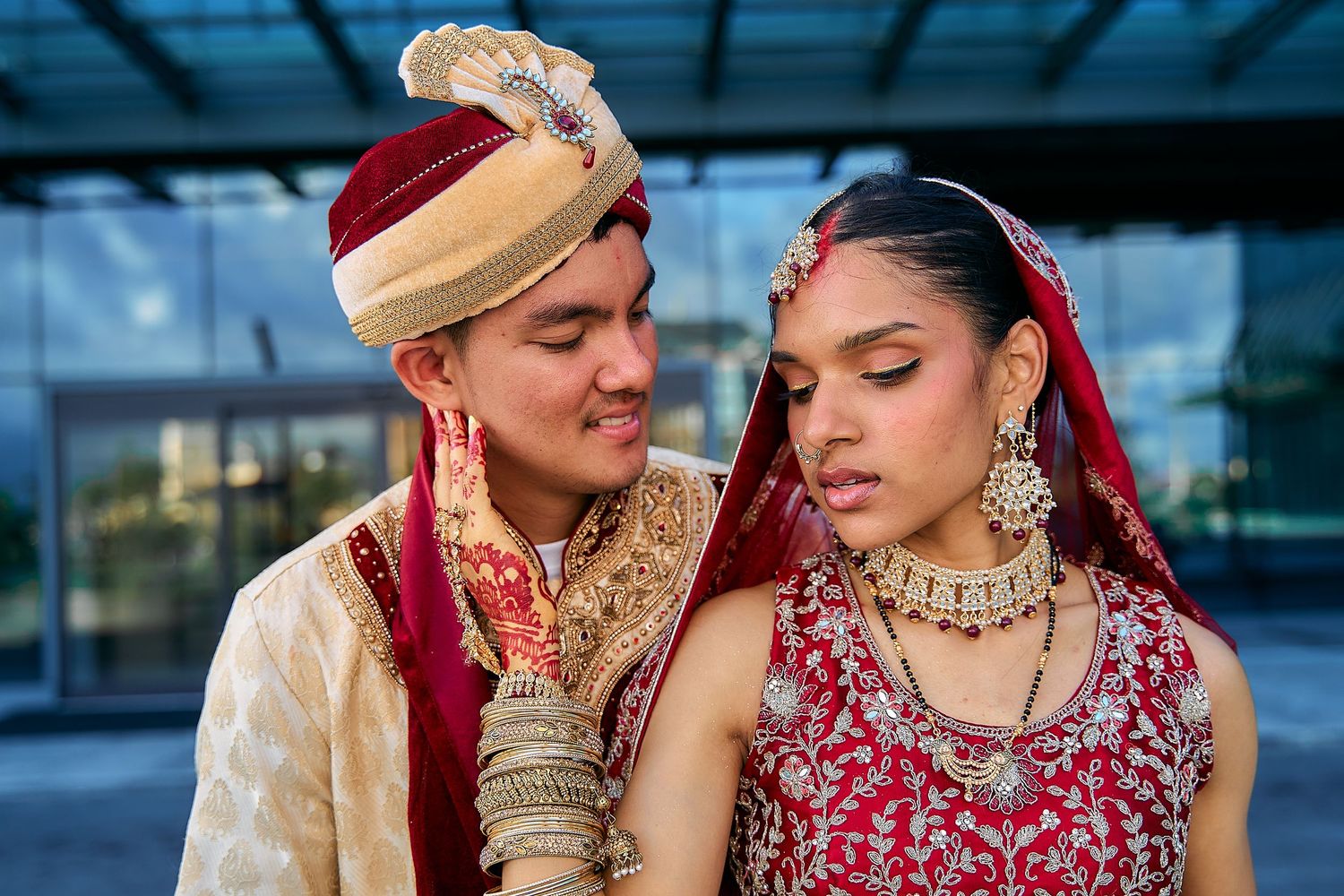 Romantic wedding photo series with couple in traditional Indian attire against blue building.
