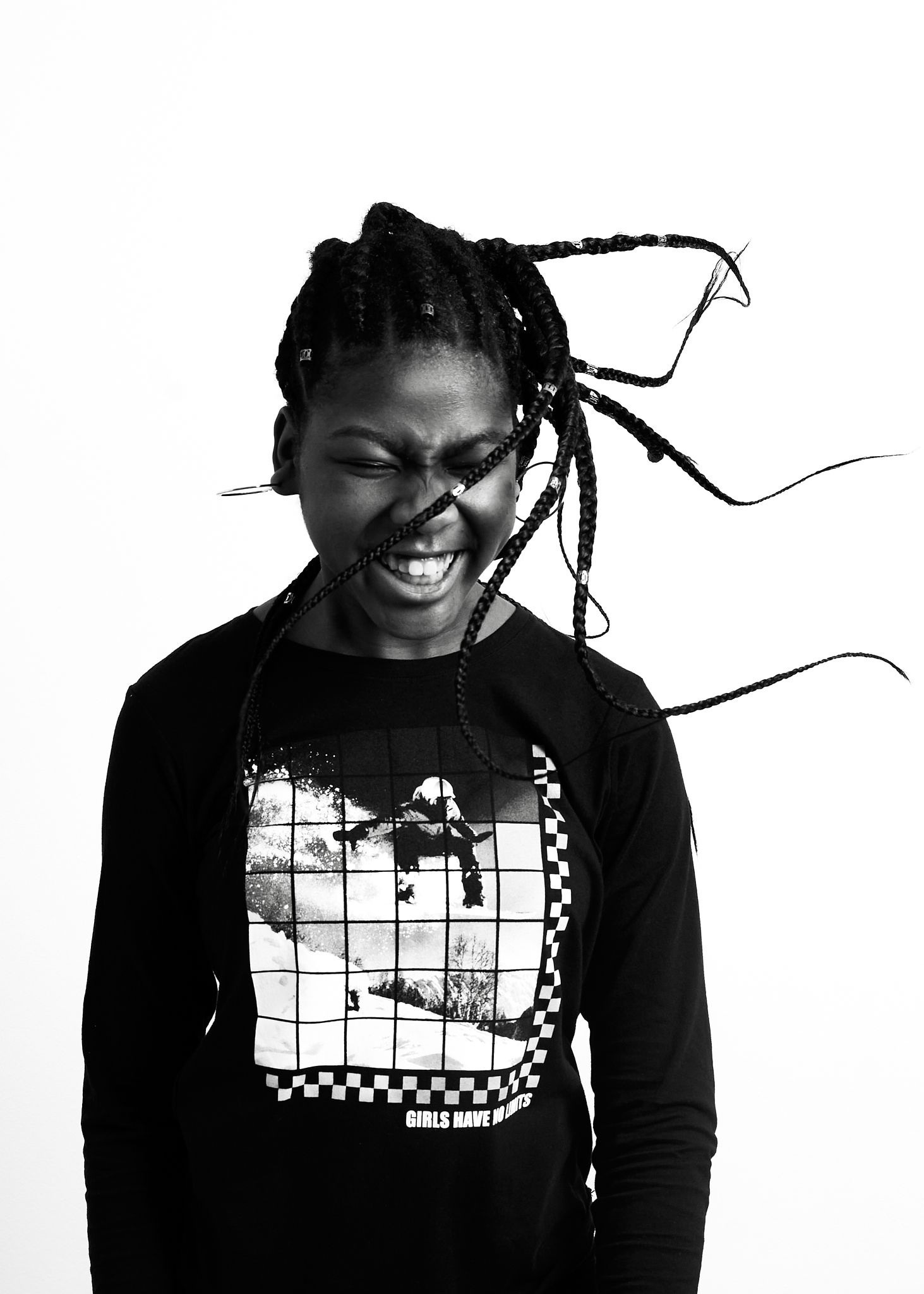 Person in black hoodie with braided hair laughing against white background.