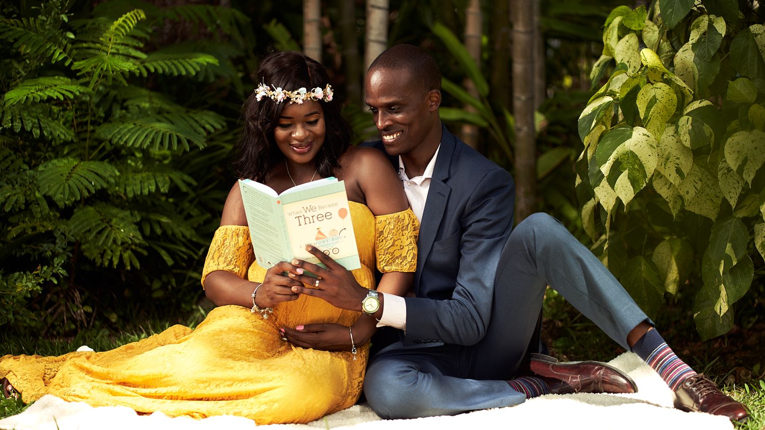 Couple sitting together outdoors in casual setting with yellow and green foliage in background.