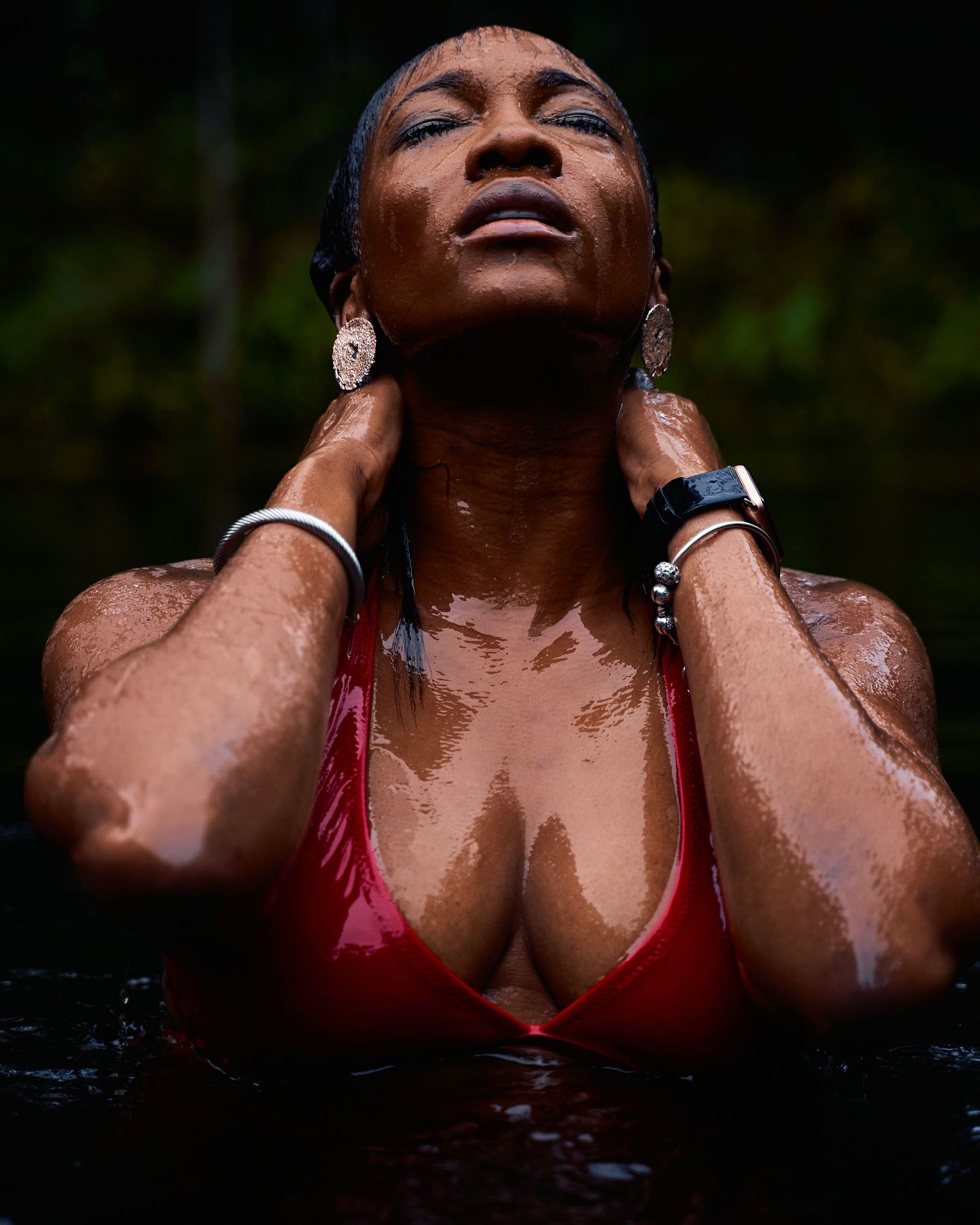 A series of artistic photographs showing someone swimming in dark water while wearing a red swimsuit.