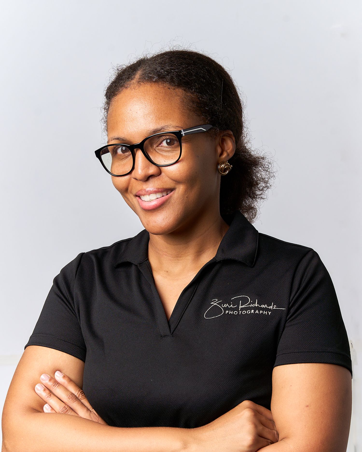Professional portraits of person in black polo shirt with glasses against white background.