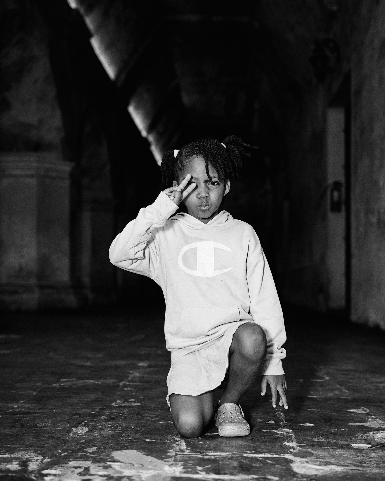 Person in a white Champion hoodie crouching in a dark corridor.